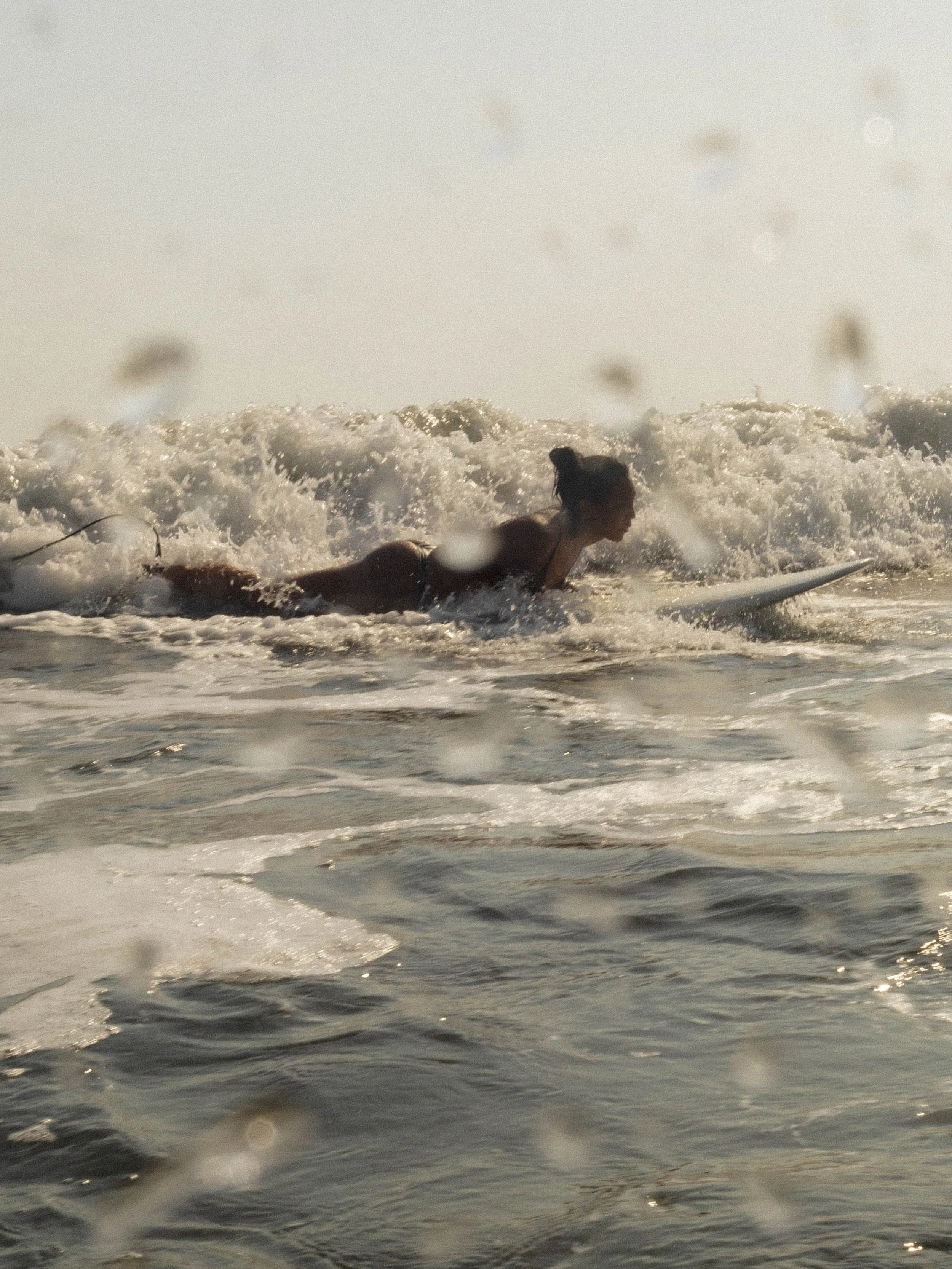 Woman paddling a longboard through whitewater while learning to surf at Still Salty Escape surf camp in Nicaragua