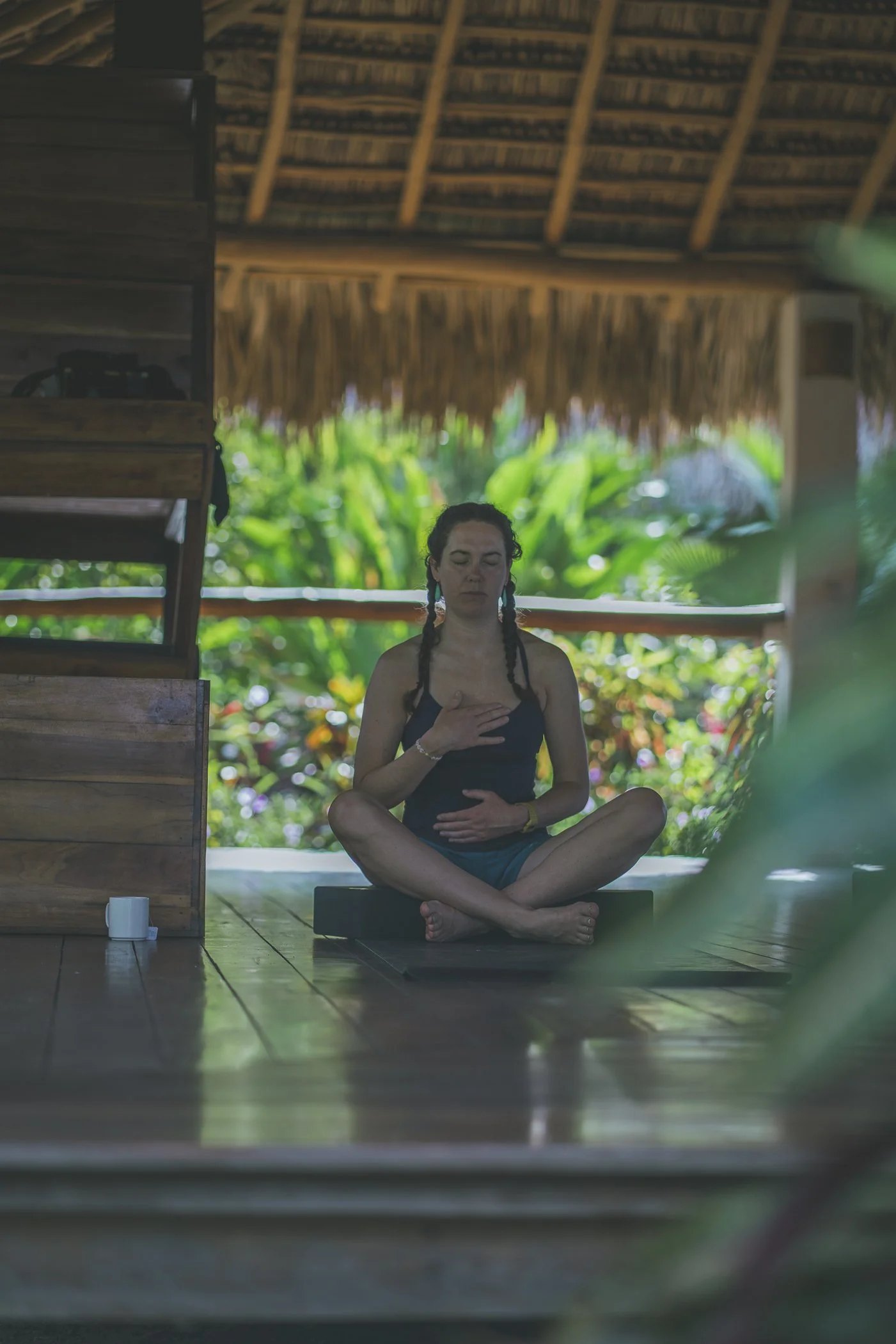 Guest meditating with a hand on her heart on the open-air deck surrounded by gardens at Still Salty Escape Nicaragua