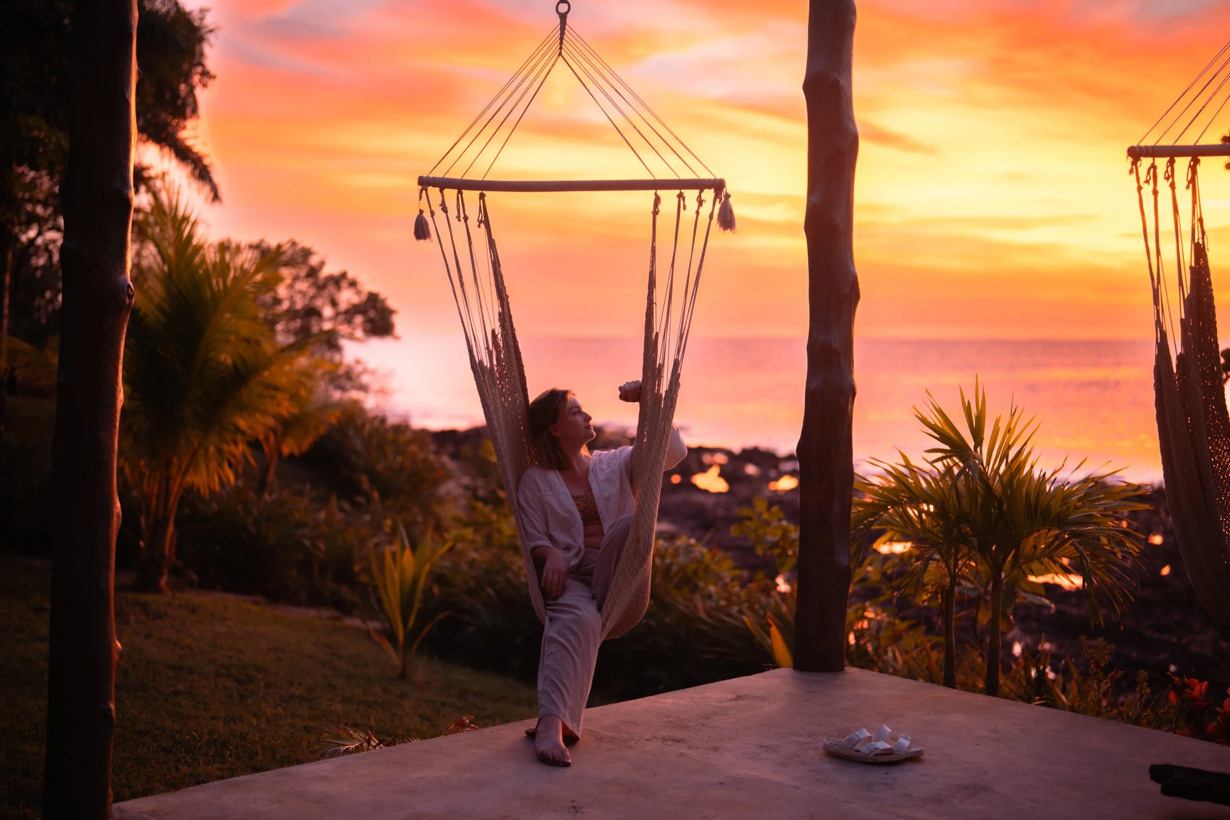 Woman relaxing in a hammock at sunset overlooking the ocean during downtime at a Northern Nicaragua surf camp