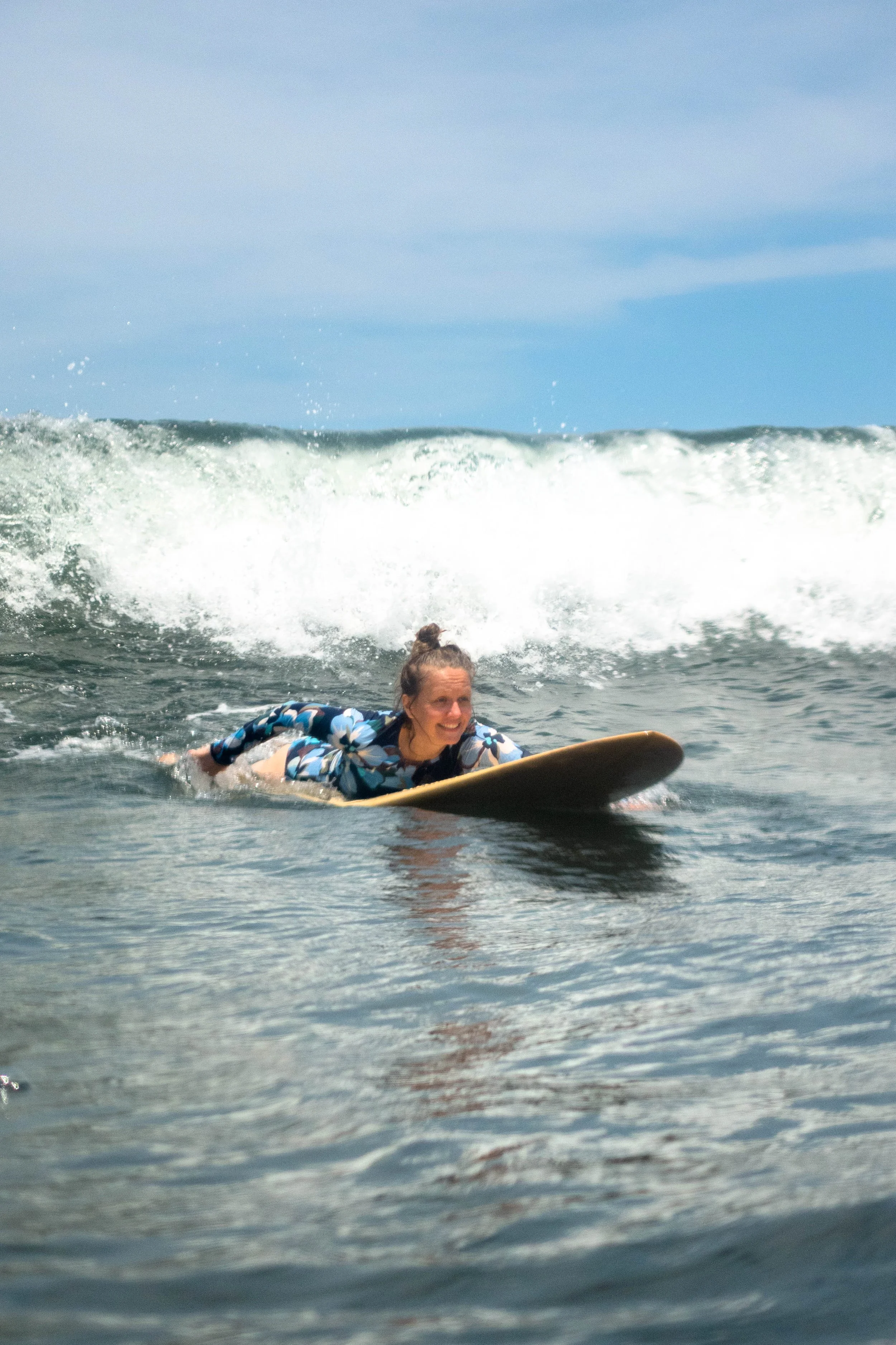 Beginner surfer girl paddling out on her board during a surf and yoga retreat in Nicaragua