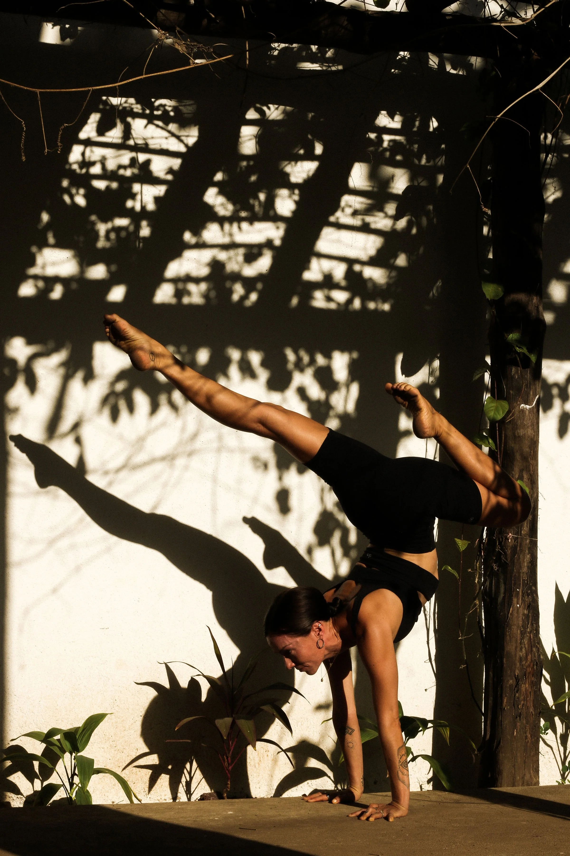 Experienced yoga teacher holding a handstand against a sunlit wall at a retreat in Nicaragua