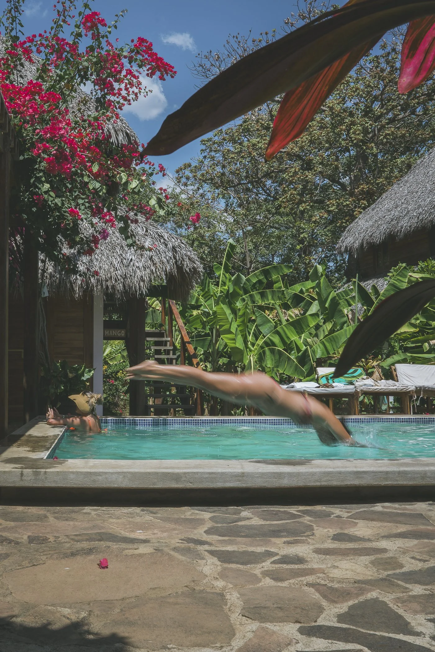 Guest diving into the private pool beside thatched cabañas at Still Salty Escape retreat venue in Nicaragua