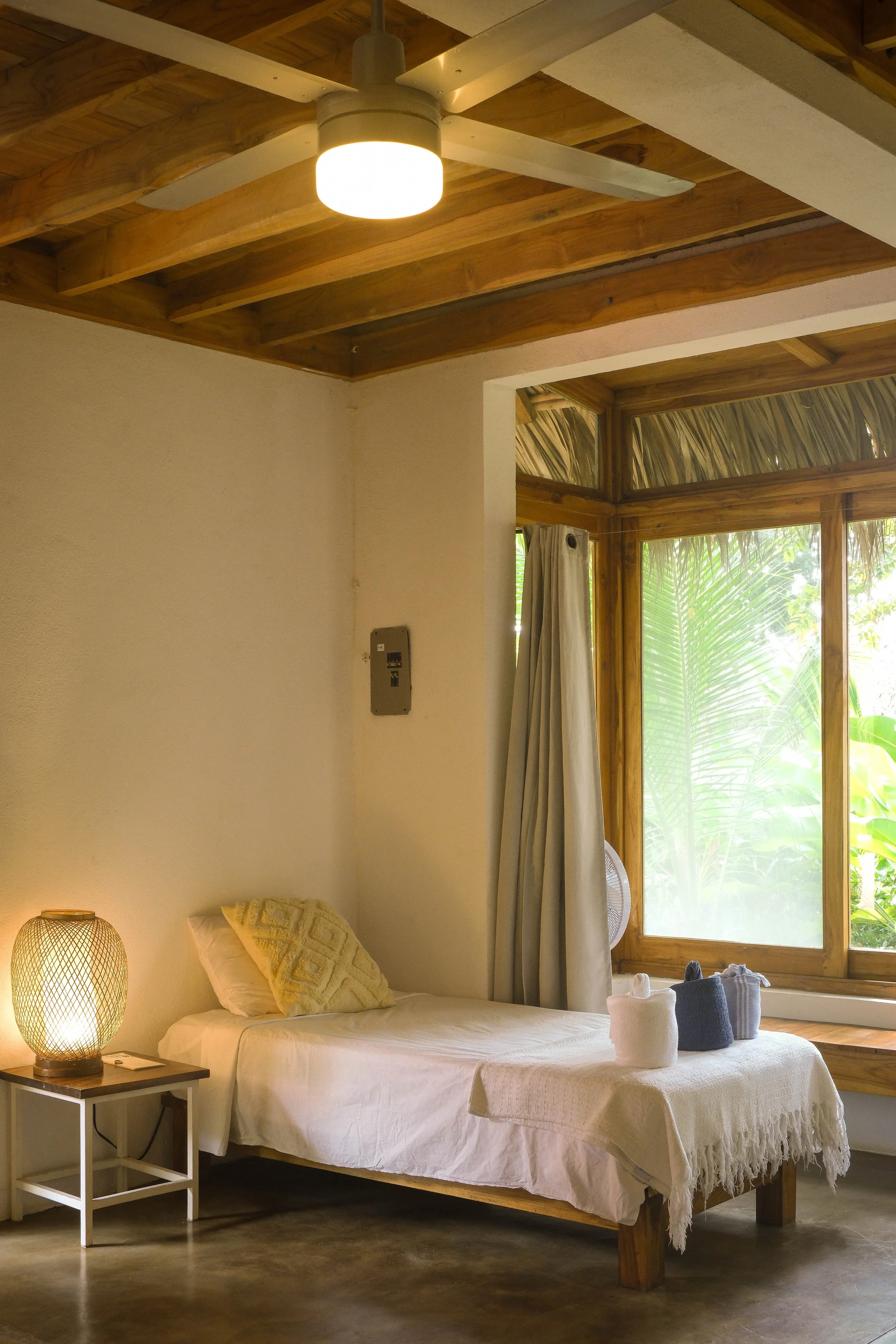 Cabaña room with a wood-beamed ceiling and a large window framing jungle views at an eco nature hotel in northern Nicaragua