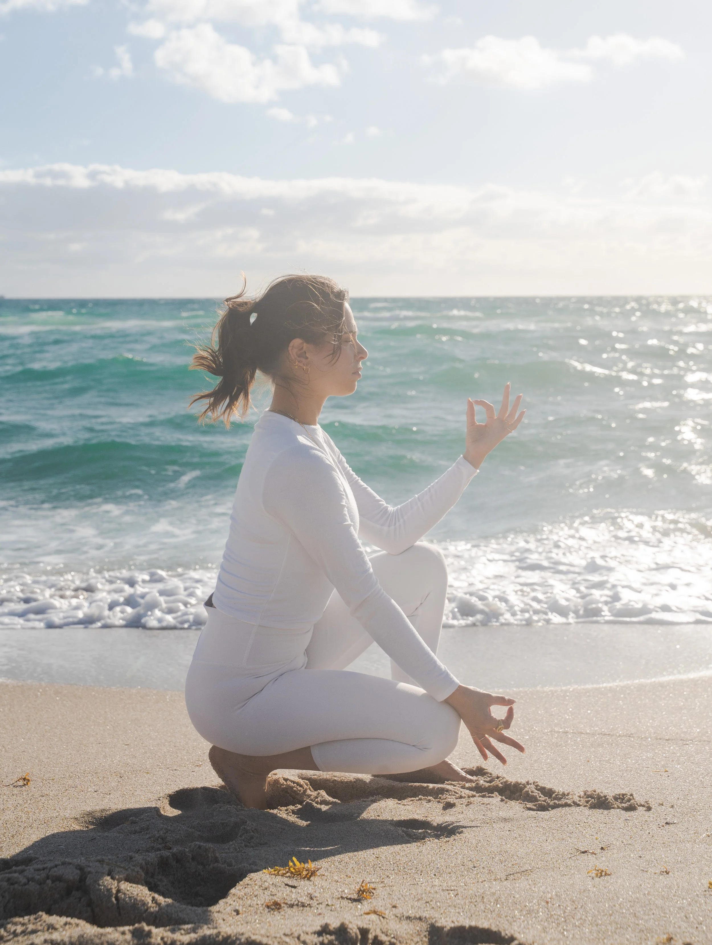 Yoga teacher balancing in toe stand pose on an uncrowded beach with waves behind her during a yoga retreat in Nicaragua