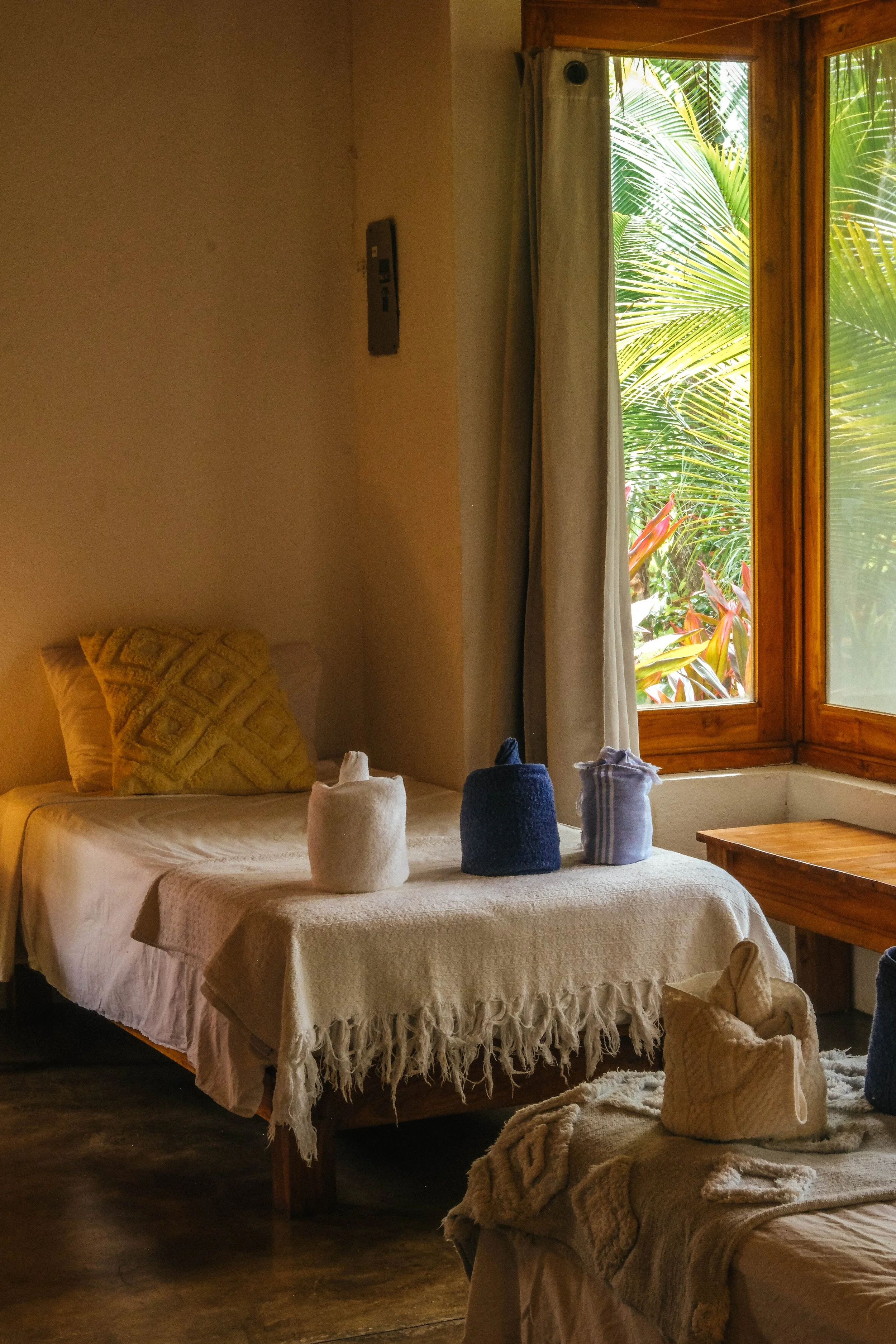 Single bed beside a garden-view window in an air-conditioned ensuite downstairs cabaña room at a Nicaragua surf and yoga retreat