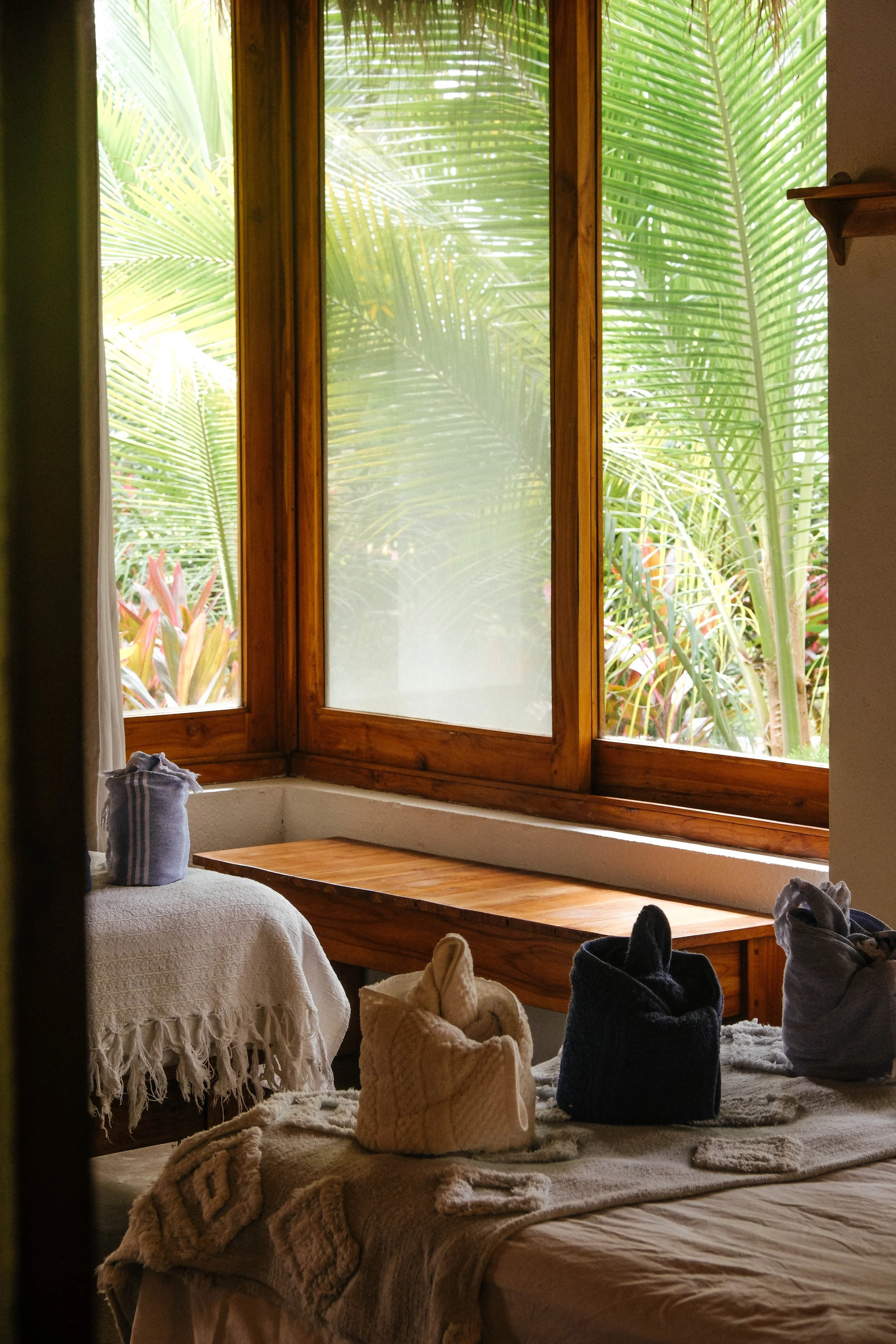 Cabaña bed and teak window bench framing lush palm garden views at a nature hotel in northern Nicaragua