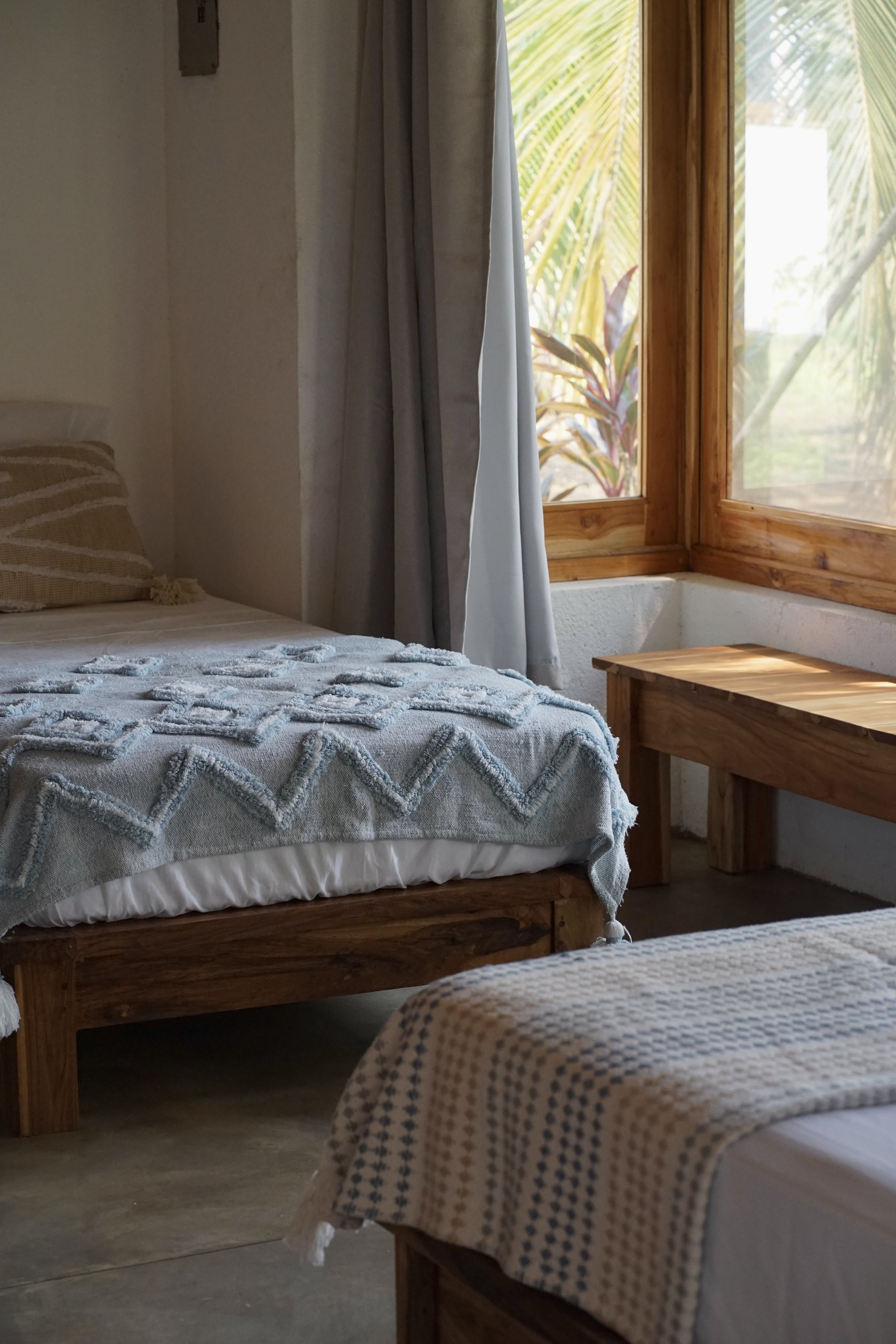Bright shared guest room with wooden beds and woven blankets at Still Salty Escape retreat venue in Nicaragua