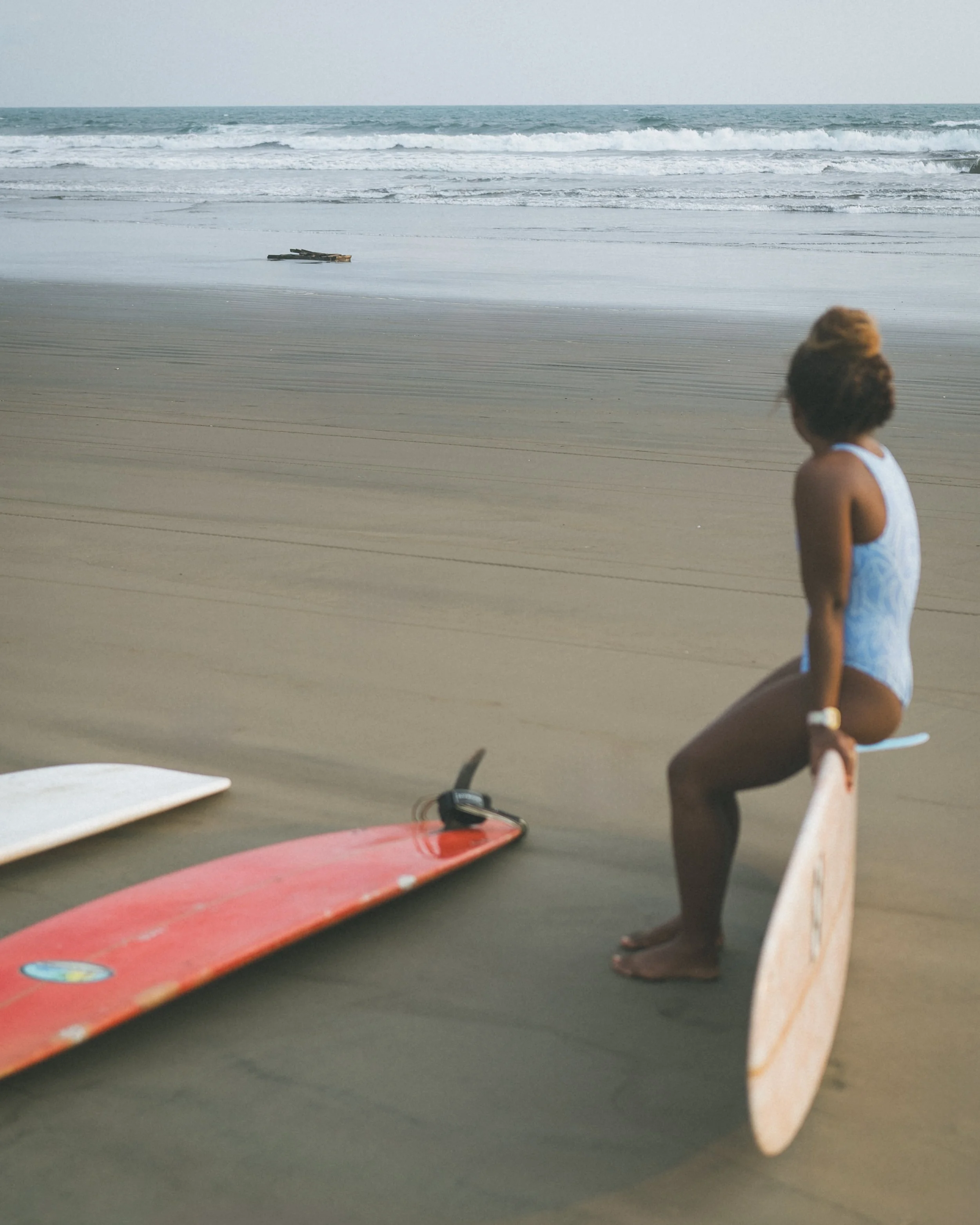 Woman sitting on a longboard on the beach watching the waves at a Nicaragua surf camp