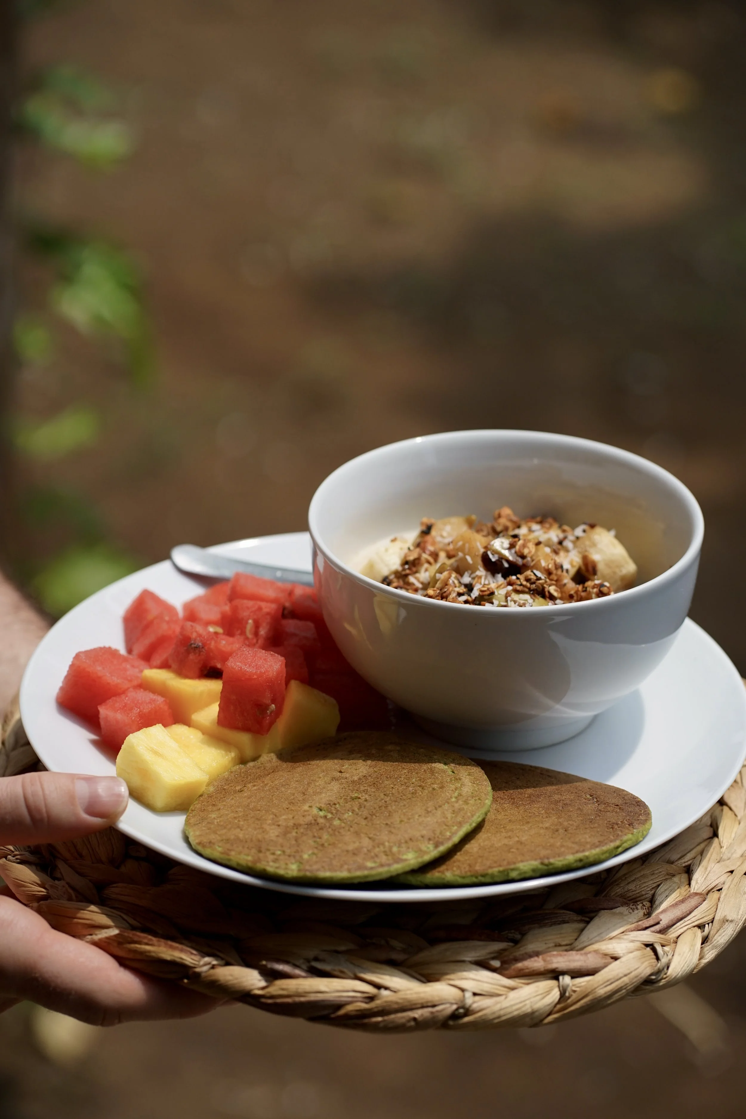 Breakfast tray with a yogurt granola bowl, fresh tropical fruit, and green pancakes at Still Salty Escape retreat in Nicaragua