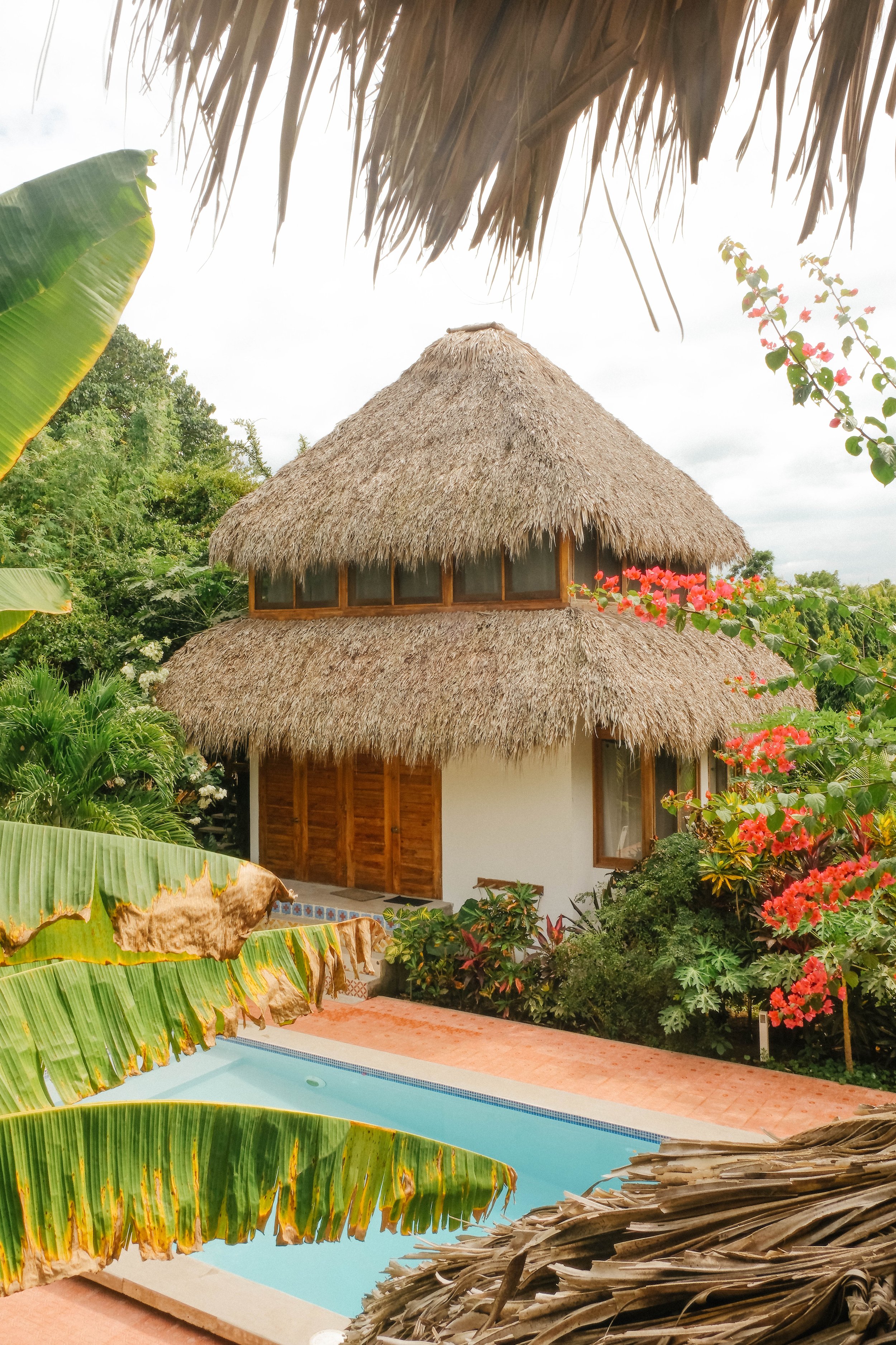 Two-story thatched-roof cabaña beside the private pool, framed by tropical gardens at Still Salty Escape nature hotel in northern Nicaragua