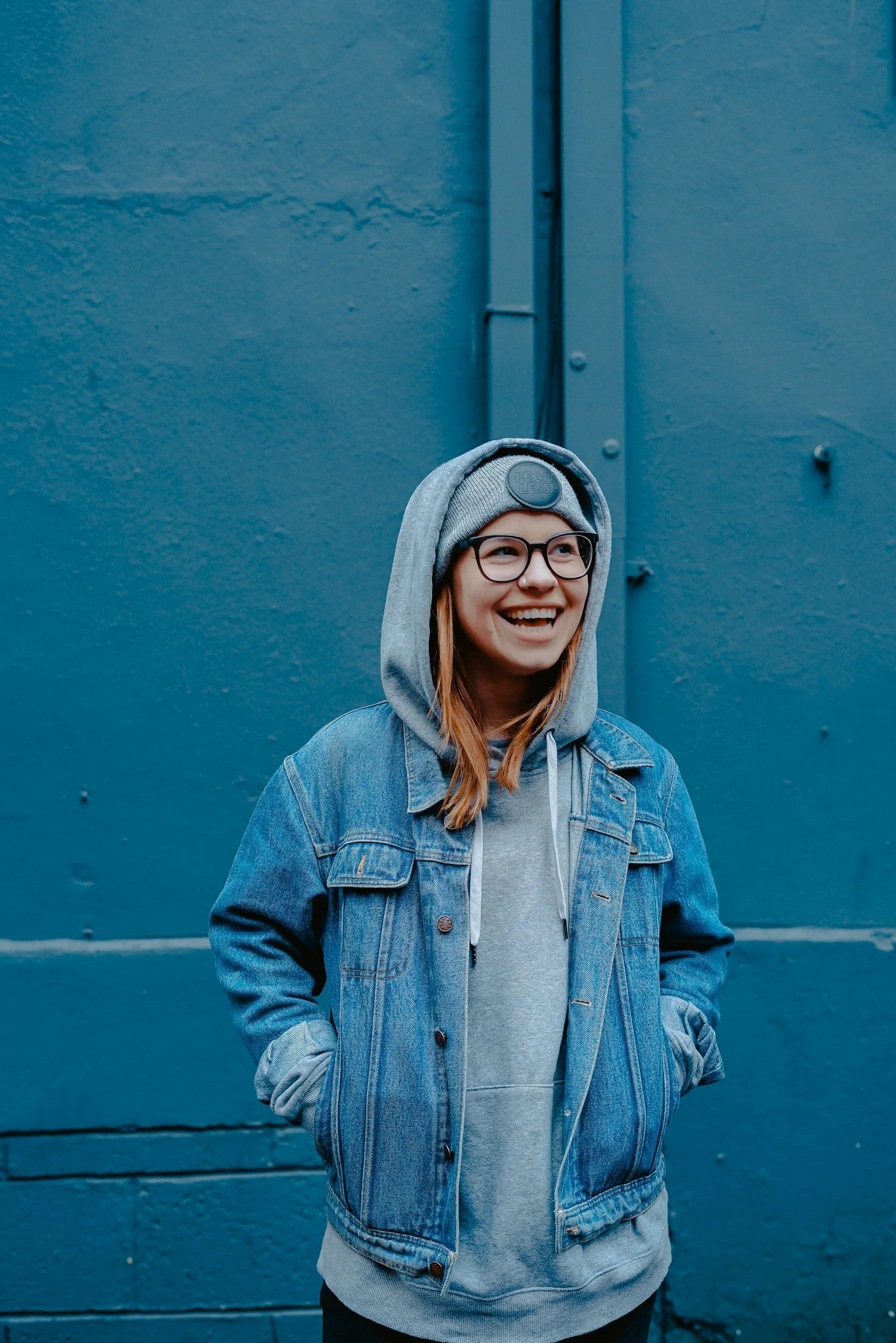Blonde teen wearing a denim jacket is looking at her left and smiling
