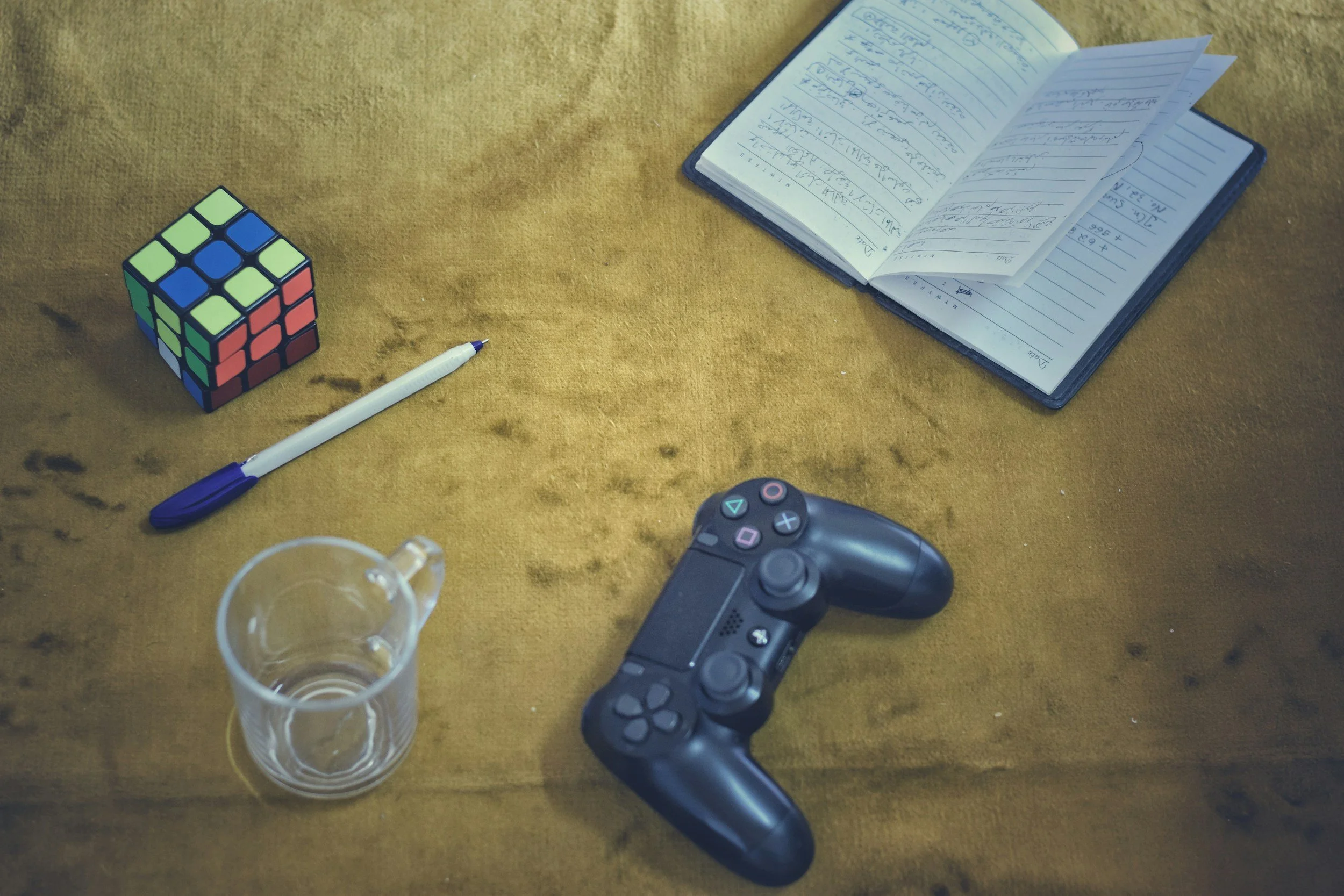 table with book videogame controller cup pen and rubix cube