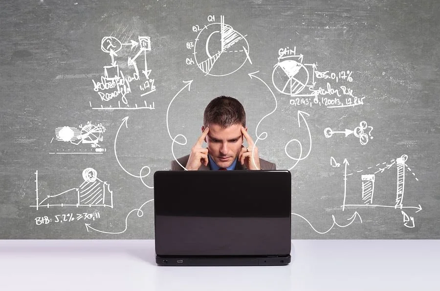 a student on a laptop while thinking about chalked equations on a grey backdrop