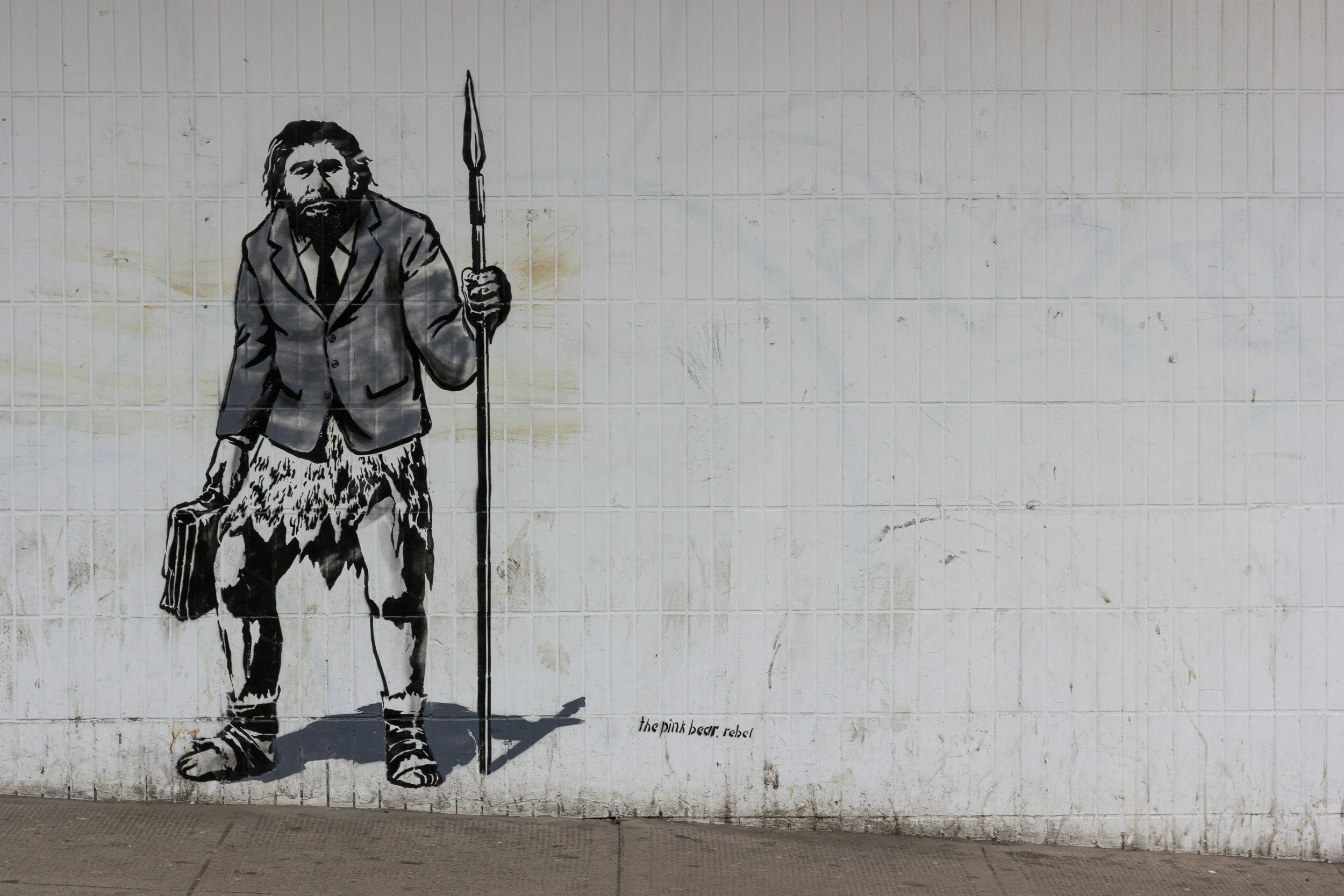 a caveman in a suit jacket spraypainted on a plastic wall