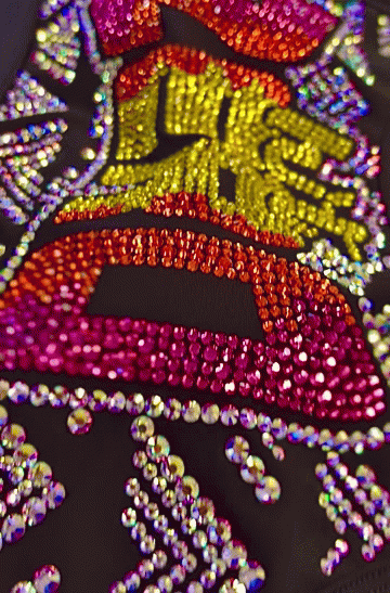 Close-up of a colorful, bejeweled design resembling lips and a face with the words "like me".