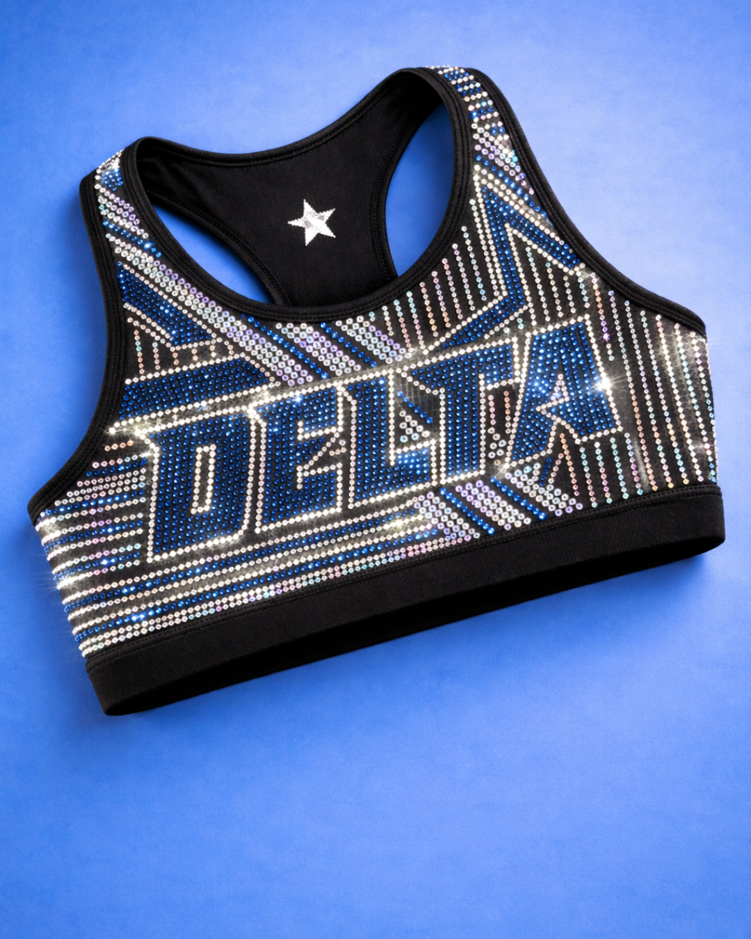 Black sports bra with rhinestone decoration spelling 'DELLA' and star design on inside, placed on a blue background.