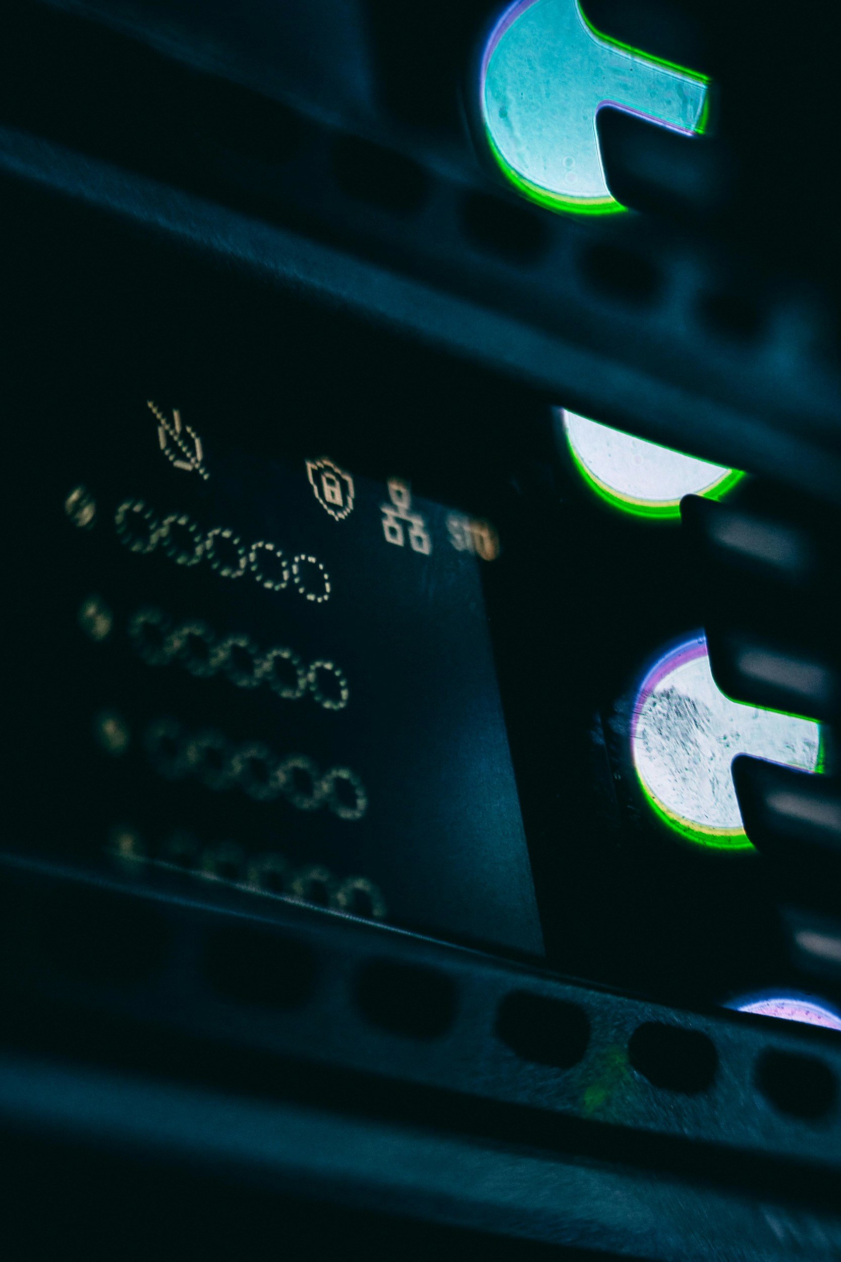 Close-up of a computer keyboard with black keys and illuminated green and purple edges, with some letters and symbols visible.
