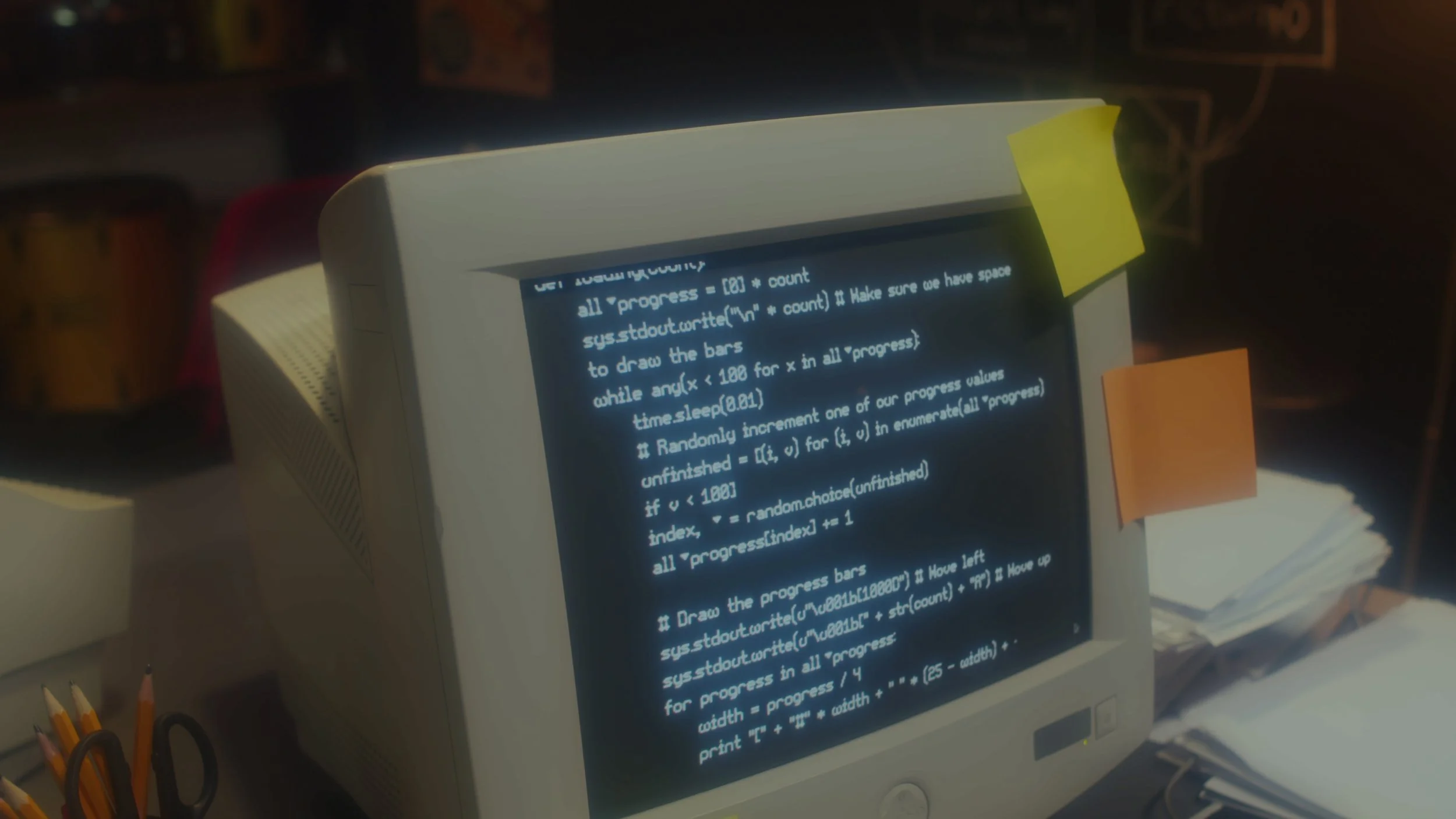 A computer monitor displaying computer code with sticky notes attached on the side, surrounded by office supplies like pens in a holder and paper stacks.