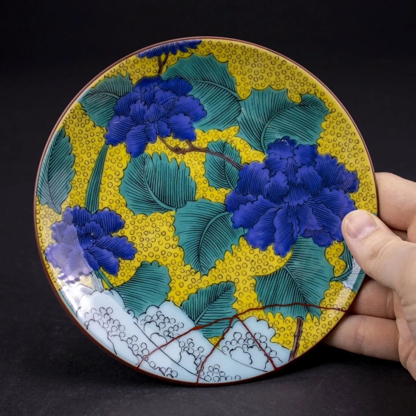 Kutani ware. We applied orange urushi because we thought it would look amazing with this colorful and beautiful design. It's hard to see in photos, but it's orange.🧡 We hope this plate will be used for a long long time. 🥰

九谷焼。この色合いとデザインにはオレンジ色の漆が合