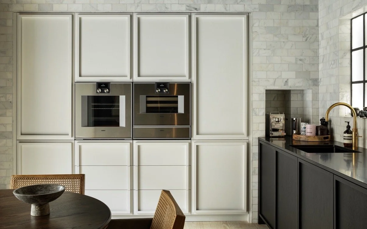 A modern bathroom with a glass-enclosed shower, two white sinks with chrome faucets, and a mirrored cabinet above the sinks, all with marble finishes.