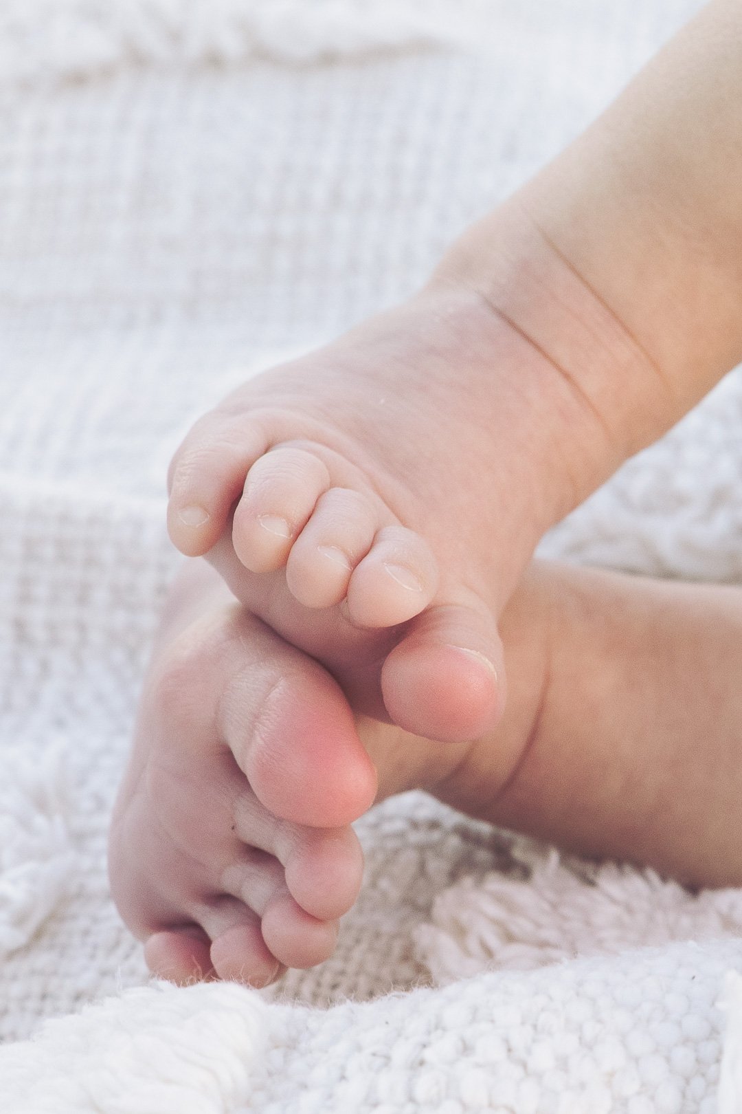 Close-up of a baby's hand gripping an adult's finger.