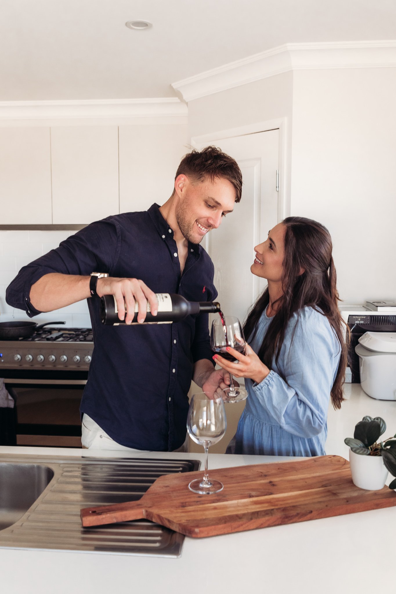 Couple pouring and enjoying wine in kitchen.
