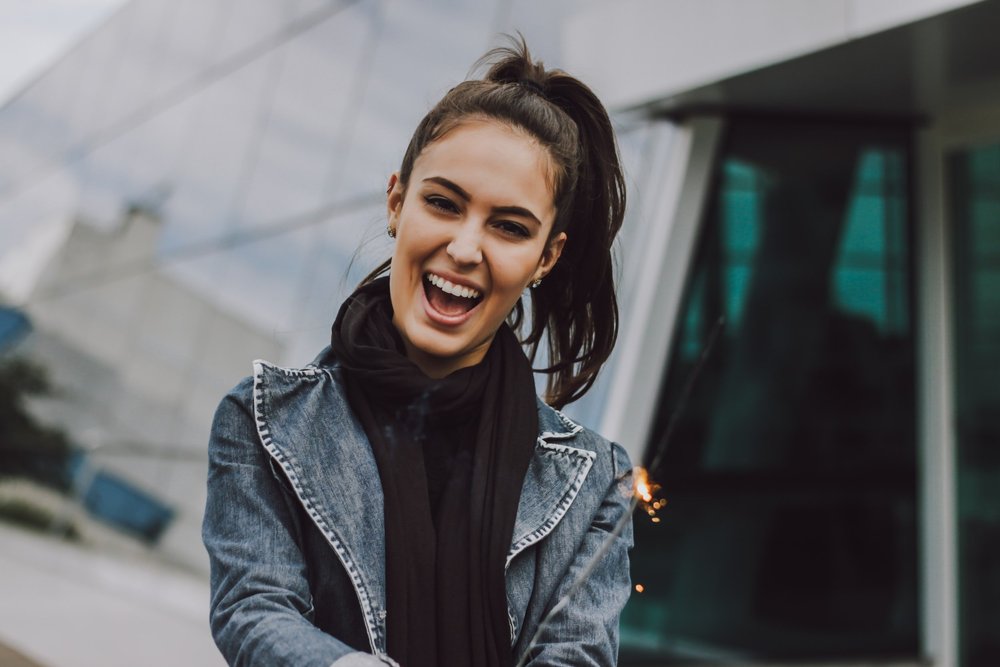 A smiling young woman in a denim jacket