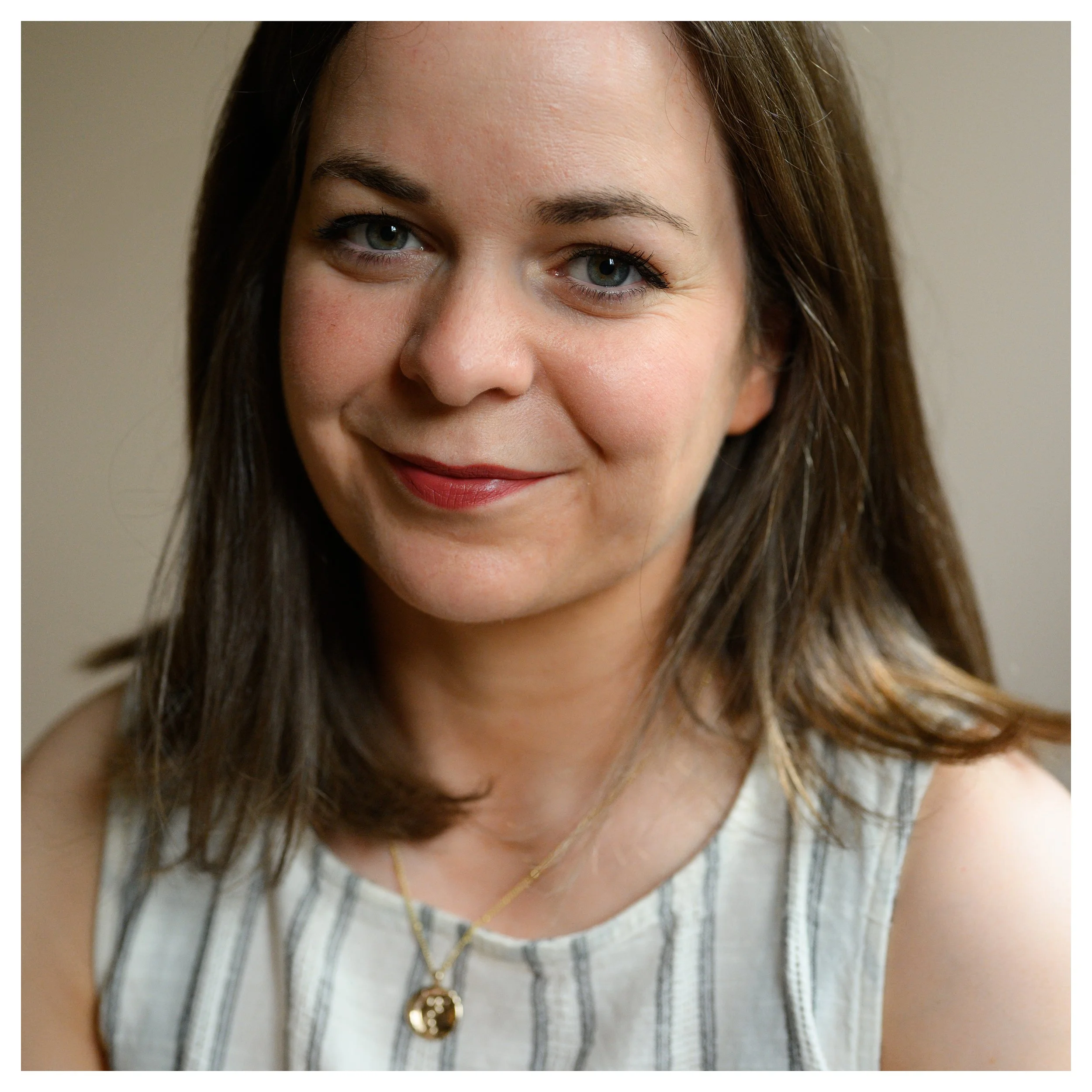 Close-up portrait of a woman with shoulder-length brown hair, blue eyes, and a gentle smile.
