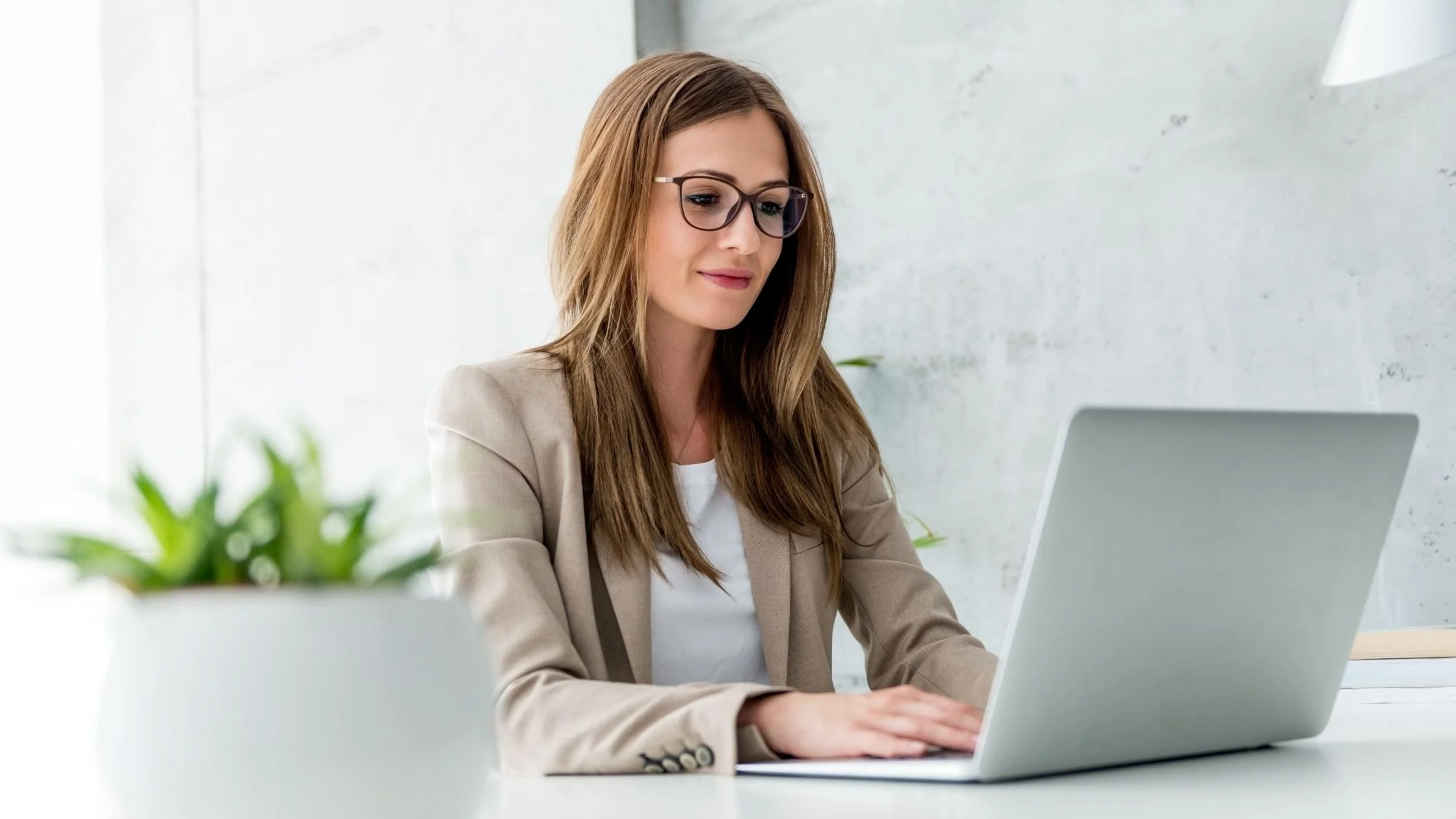 successful professionally dressed business woman using a laptop on her minimal and clean office