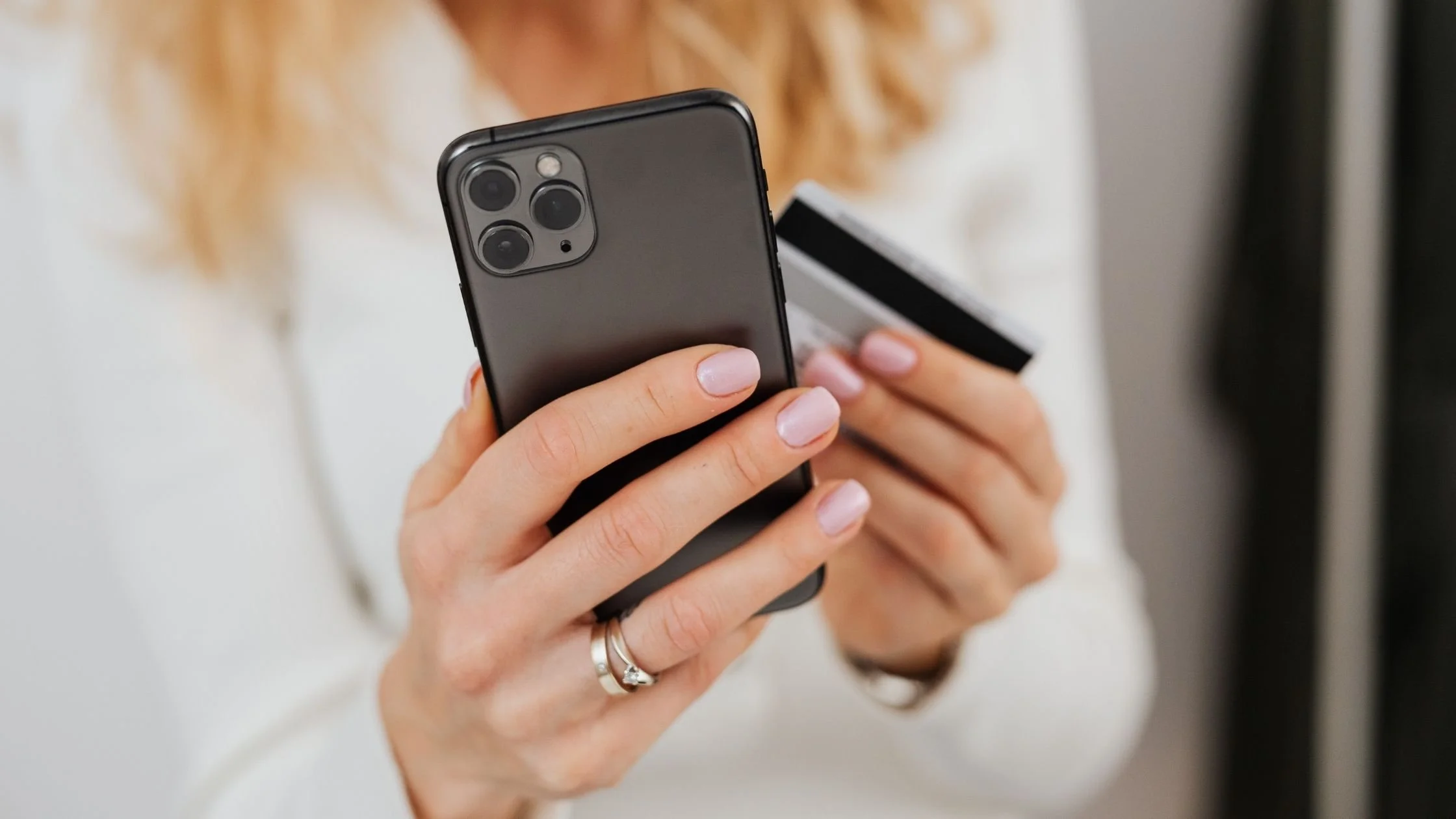 woman using phone for online shopping while holding her credit card