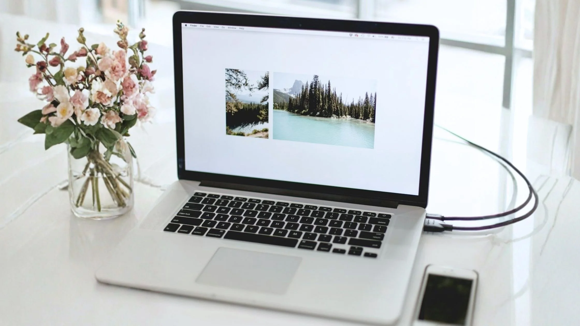 minimalist white desk with a laptop and phone near an open window