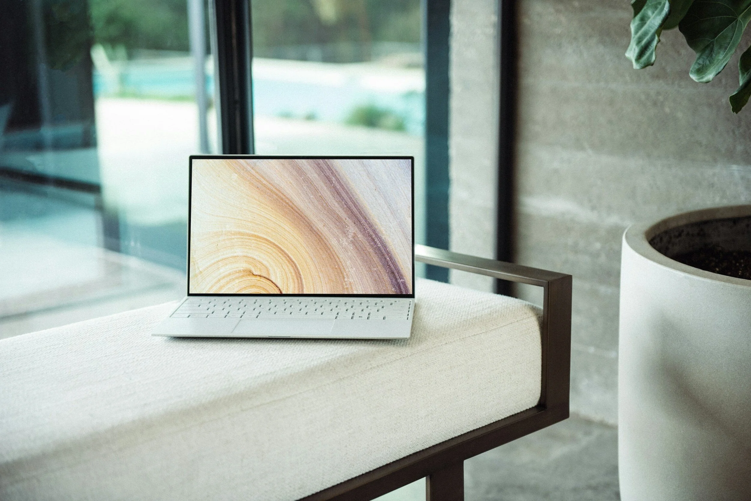 An open laptop displaying an abstract wallpaper, sitting on a minimalist white bench to represent strategic website design and brand communication