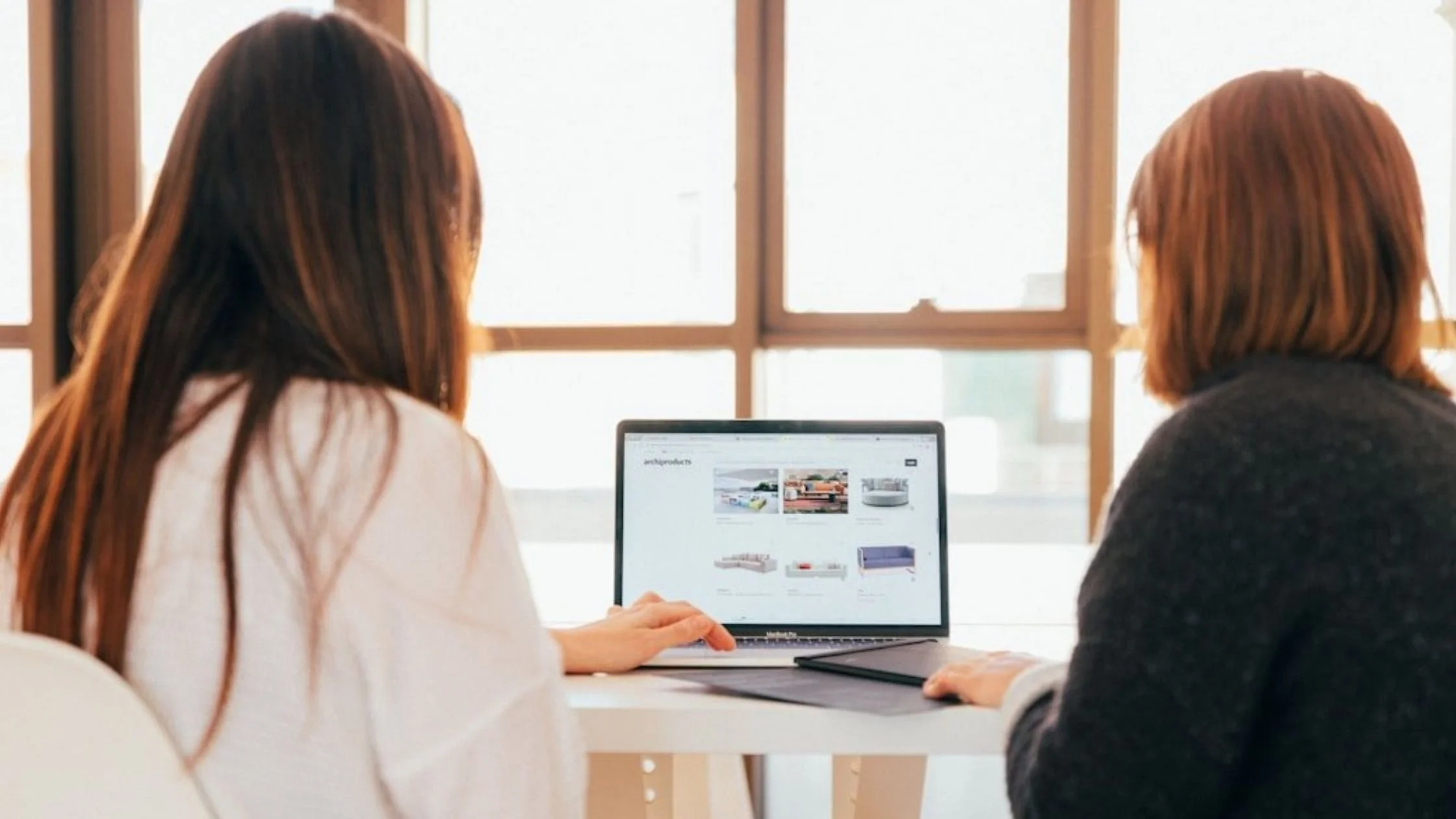 Two women working on a laptop collaborating together