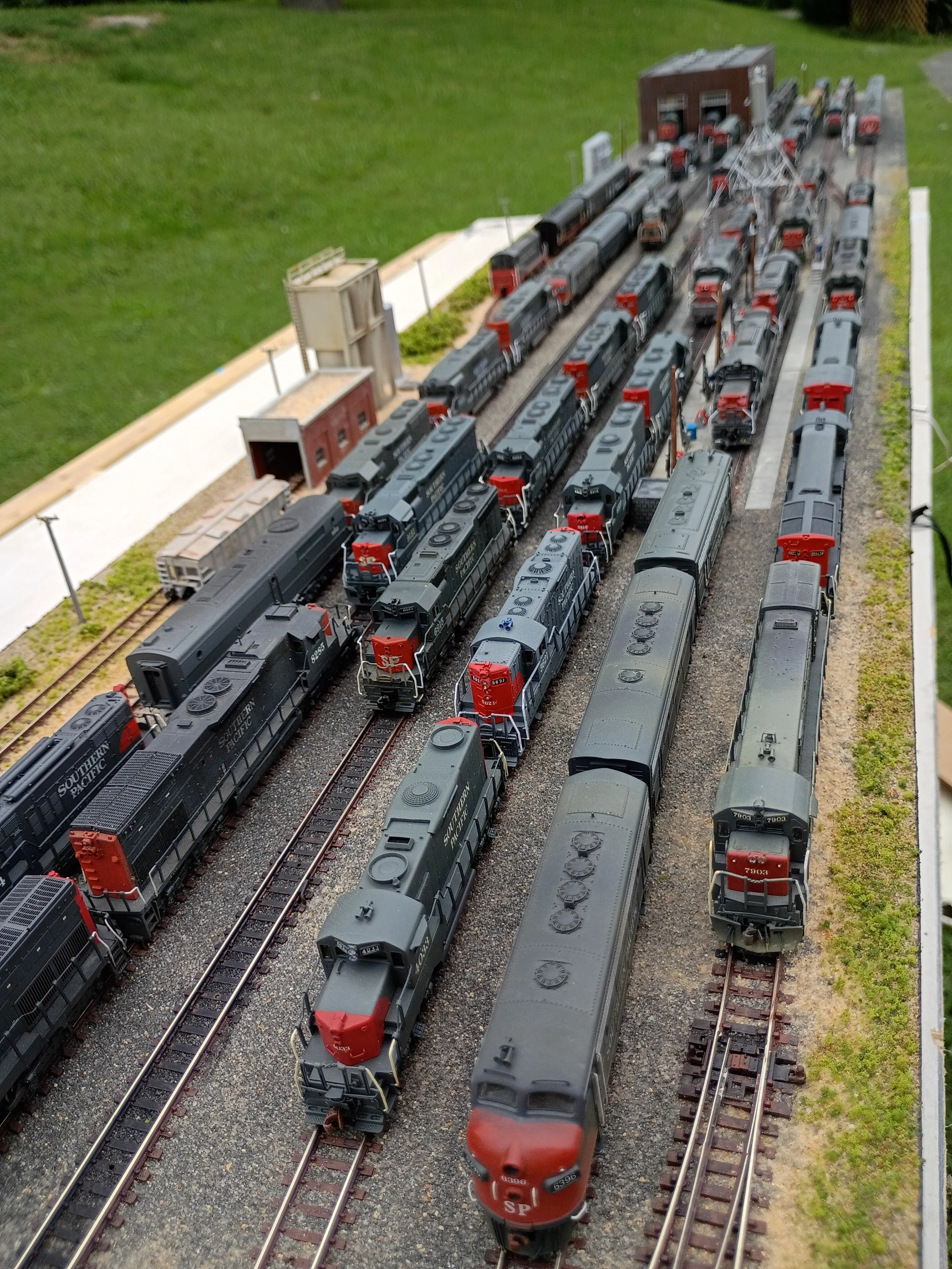 A detailed model train layout with multiple trains on tracks, buildings, and surrounding scenery.