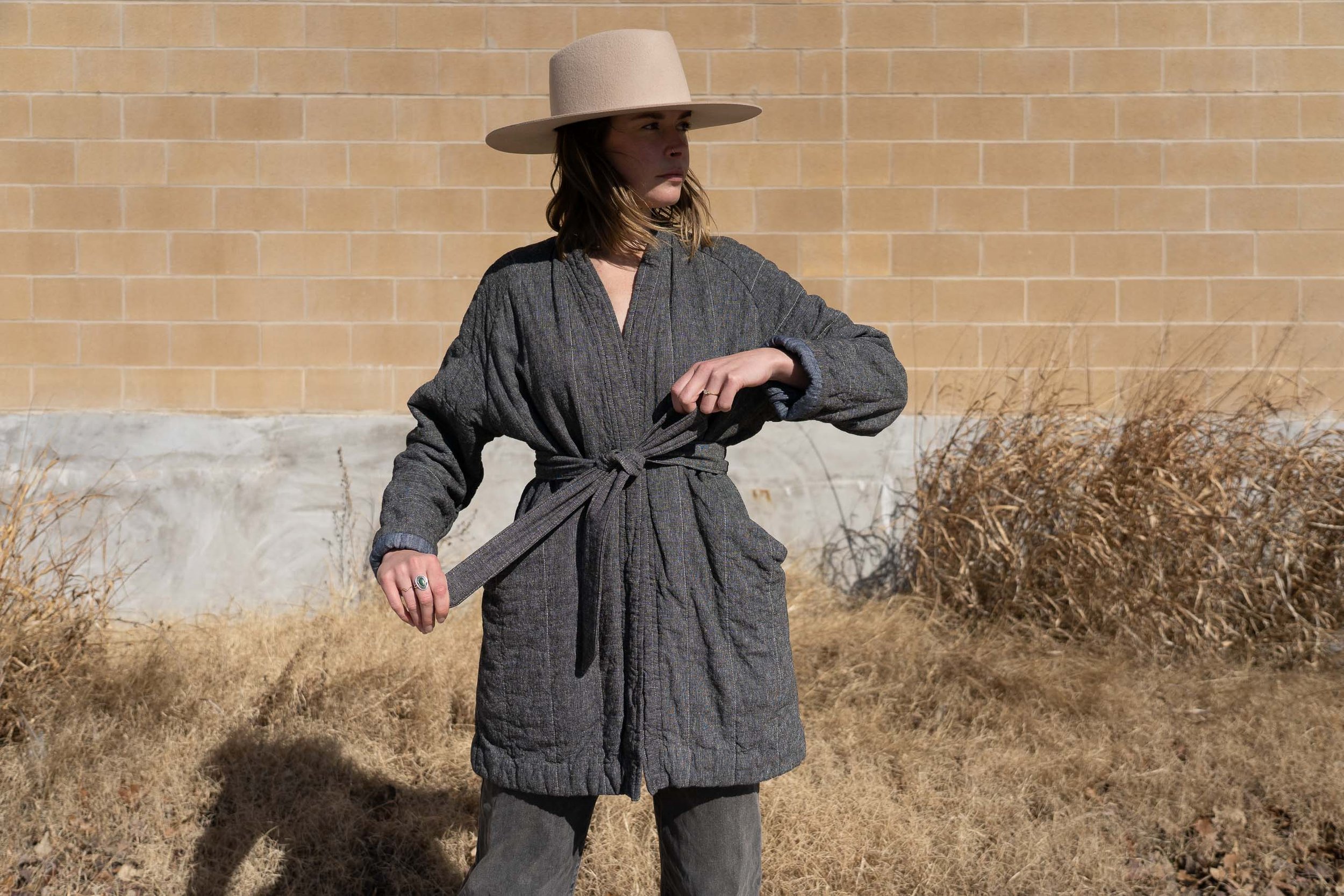 woman wearing grey cotton and linen quilted coat with a grey tied belt