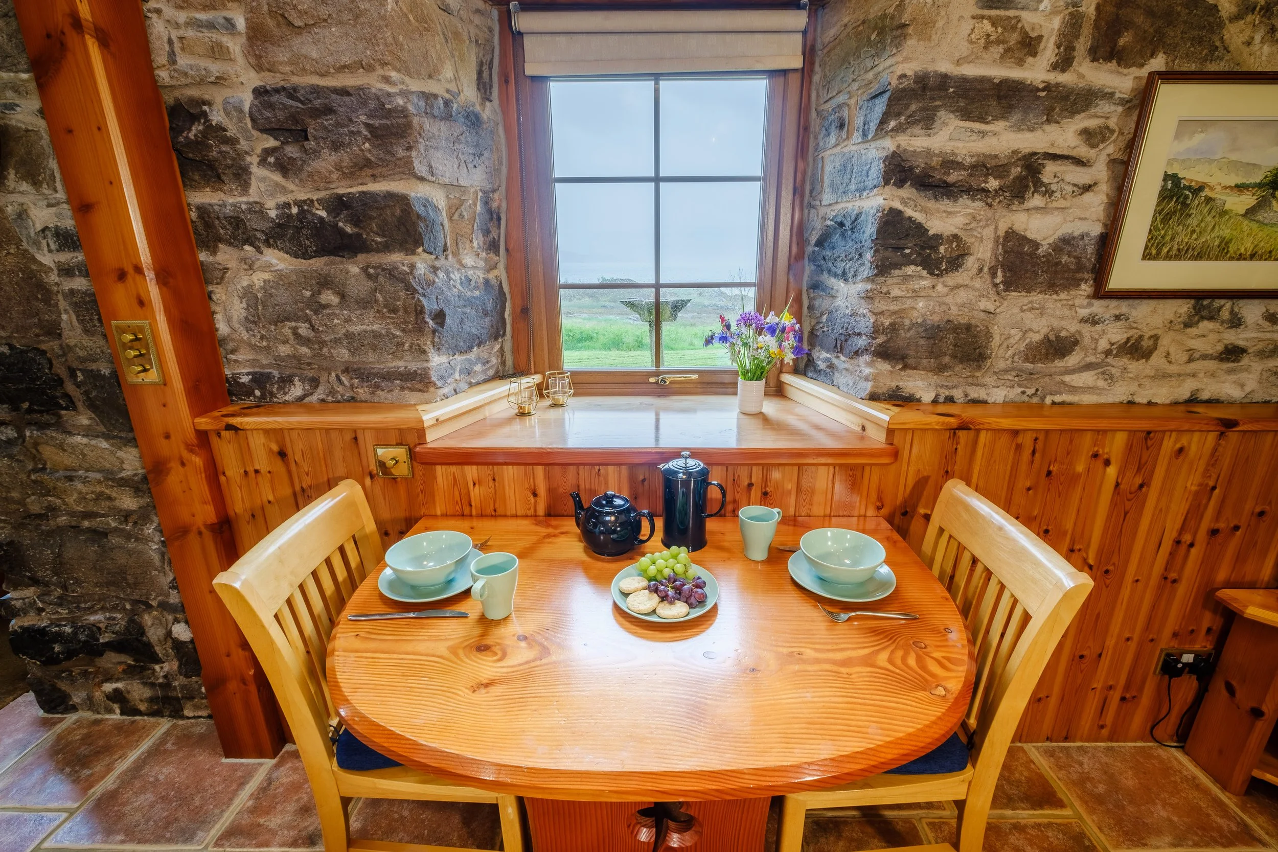 Dining table with view of bird feared and Cozy living room with wood burnign stove. Camas bàn cottage, self catering cottage for 2 -4 people on the shorefront of Loch Sunart, Ardnamurchan (Copy)