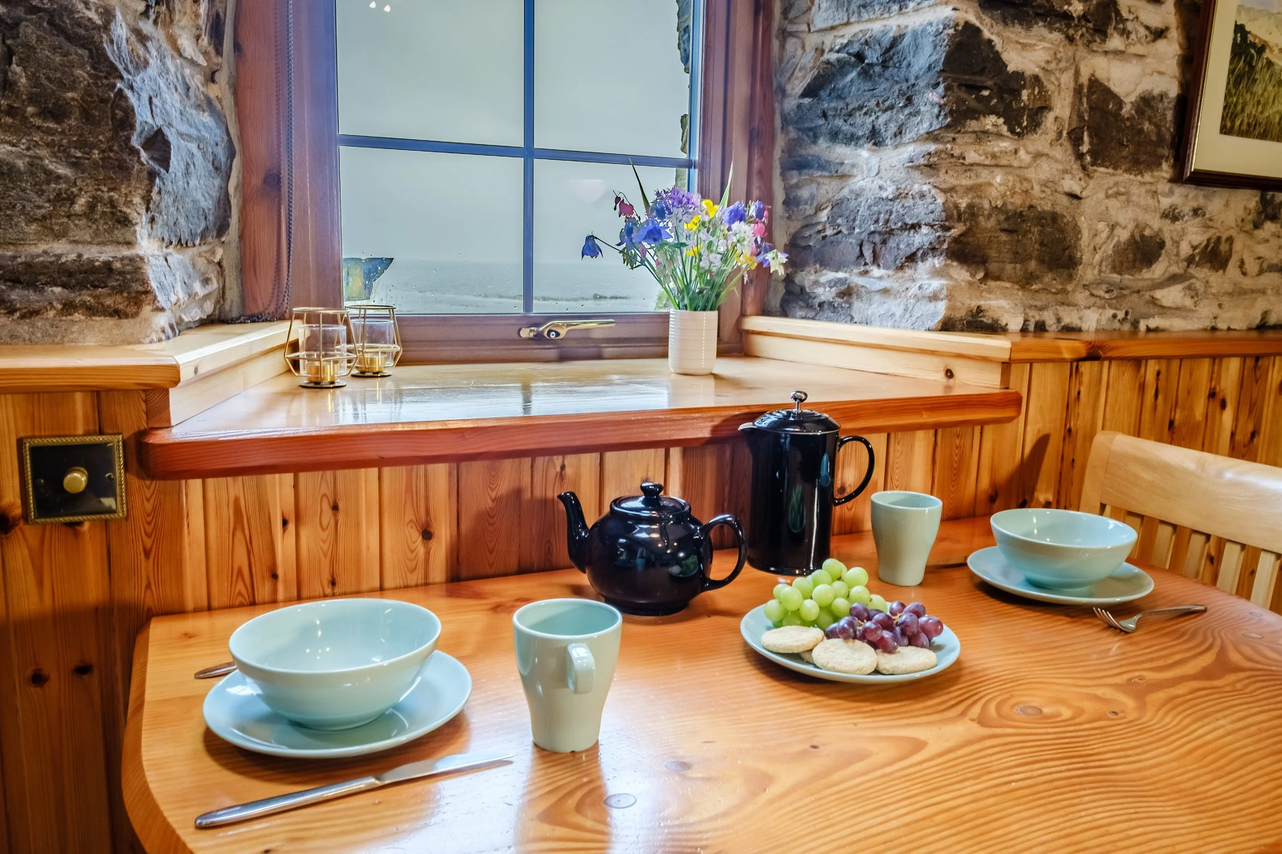 Dining table with view over bird feeder and Cozy living room with wood burnign stove. Camas bàn cottage, self catering cottage for 2 -4 people on the shorefront of Loch Sunart, Ardnamurchan (Copy)