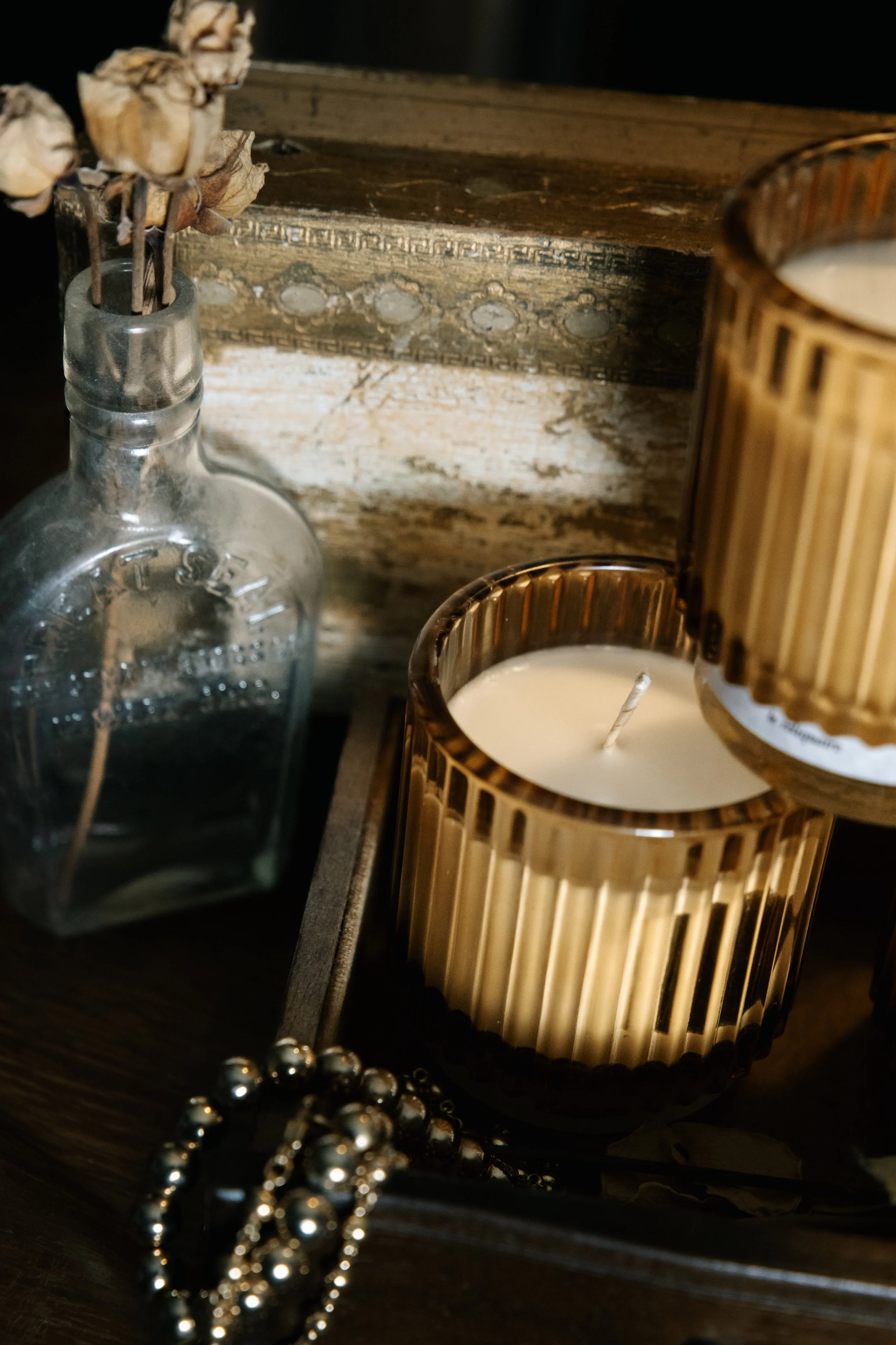Hand-poured Rose candle from Le Reliquaire burning beside vintage mirror and dried florals, evoking memory-rich Turkish rose and cardamom scent.