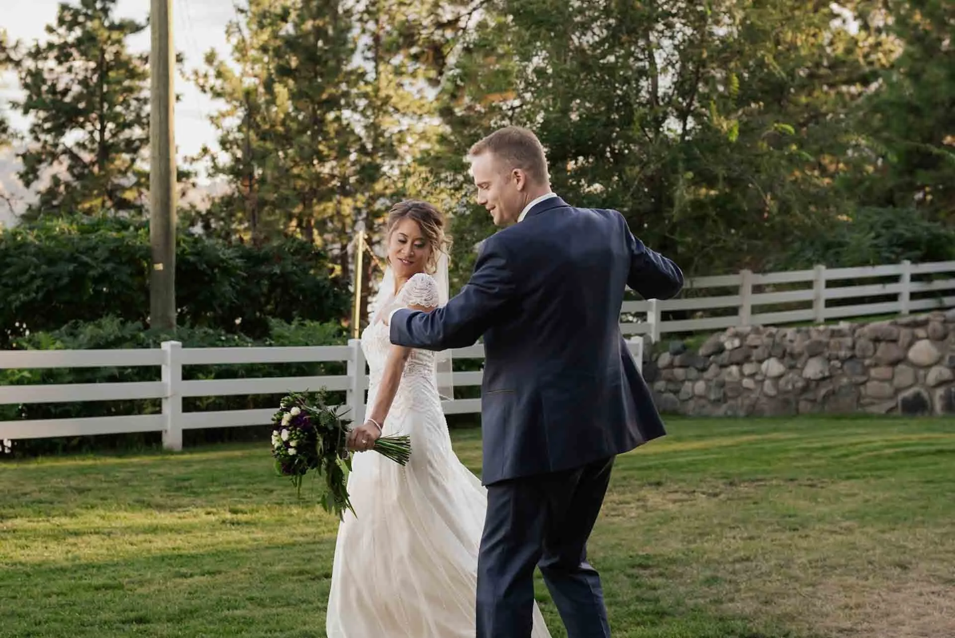 bride and groom dancing in a field 