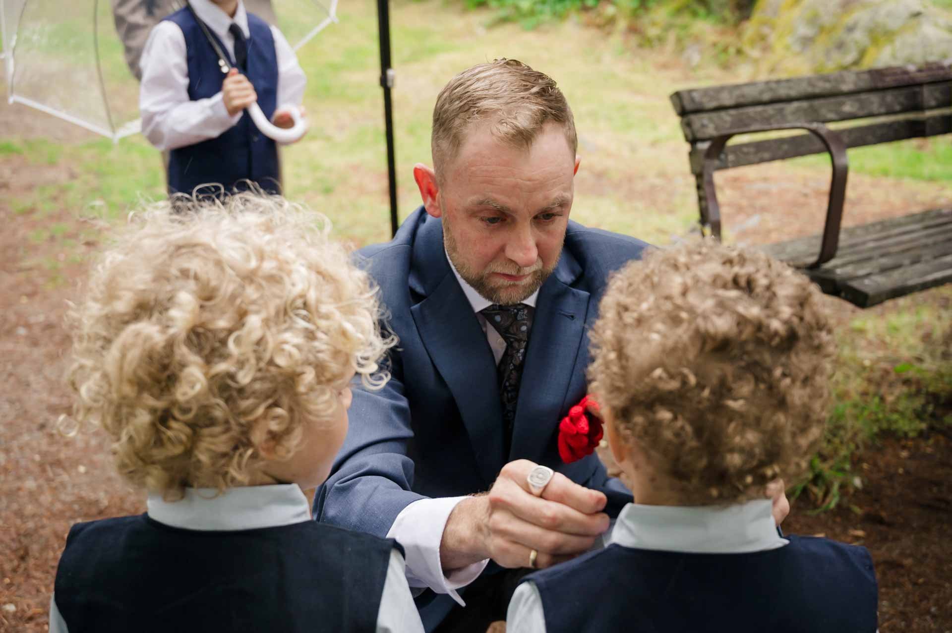 man scrouching infront of 2 boys as he fixes one of their ties