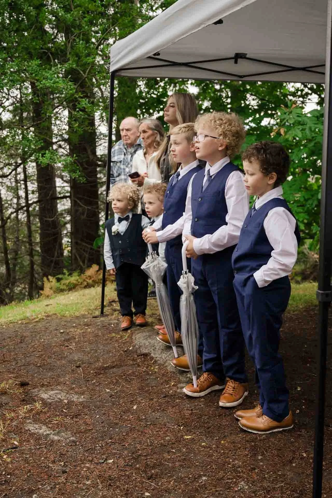 a row of kids and adults standing under a tent