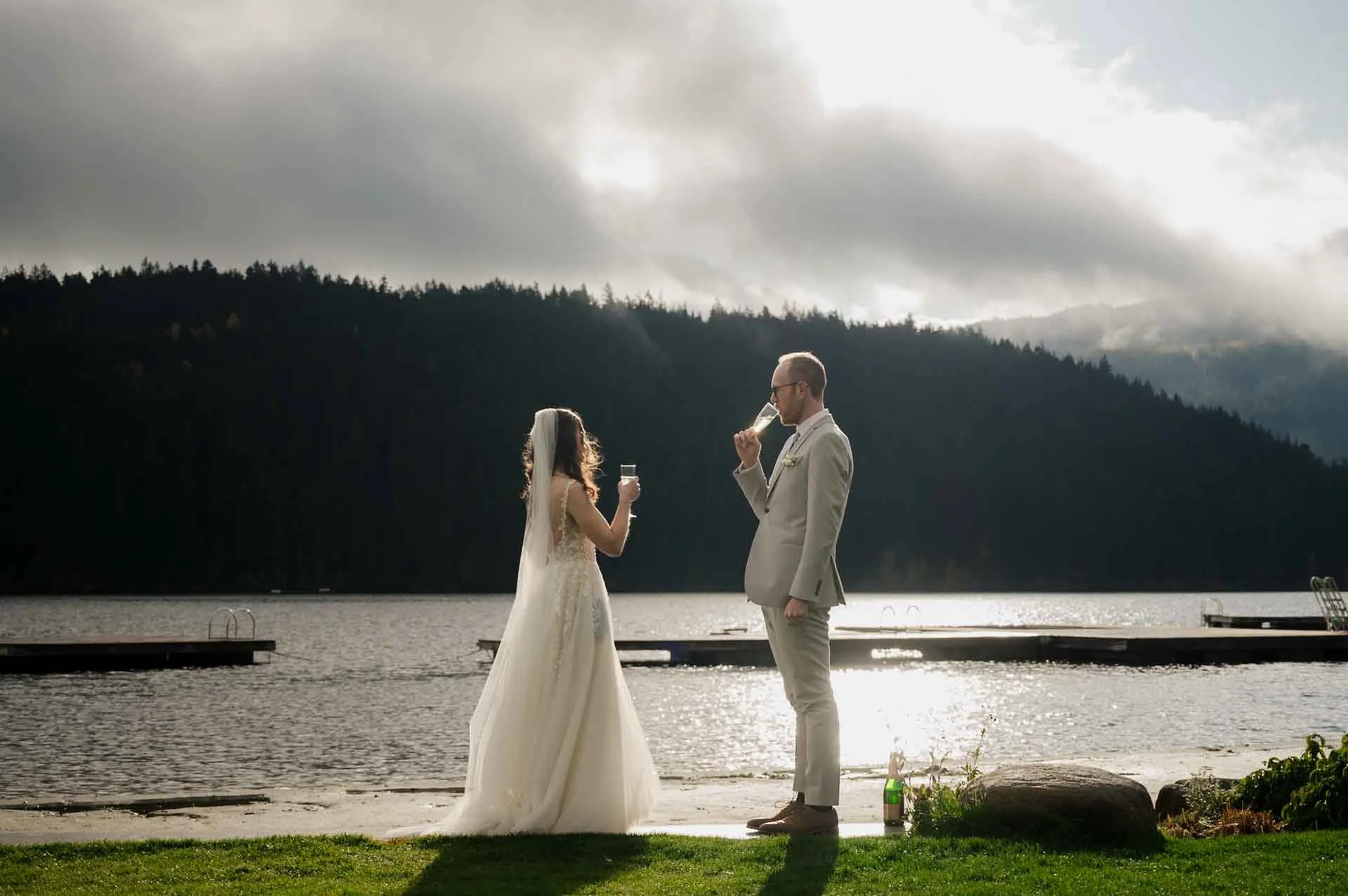 bride and groom enjoying a glass of bubbly by the lake