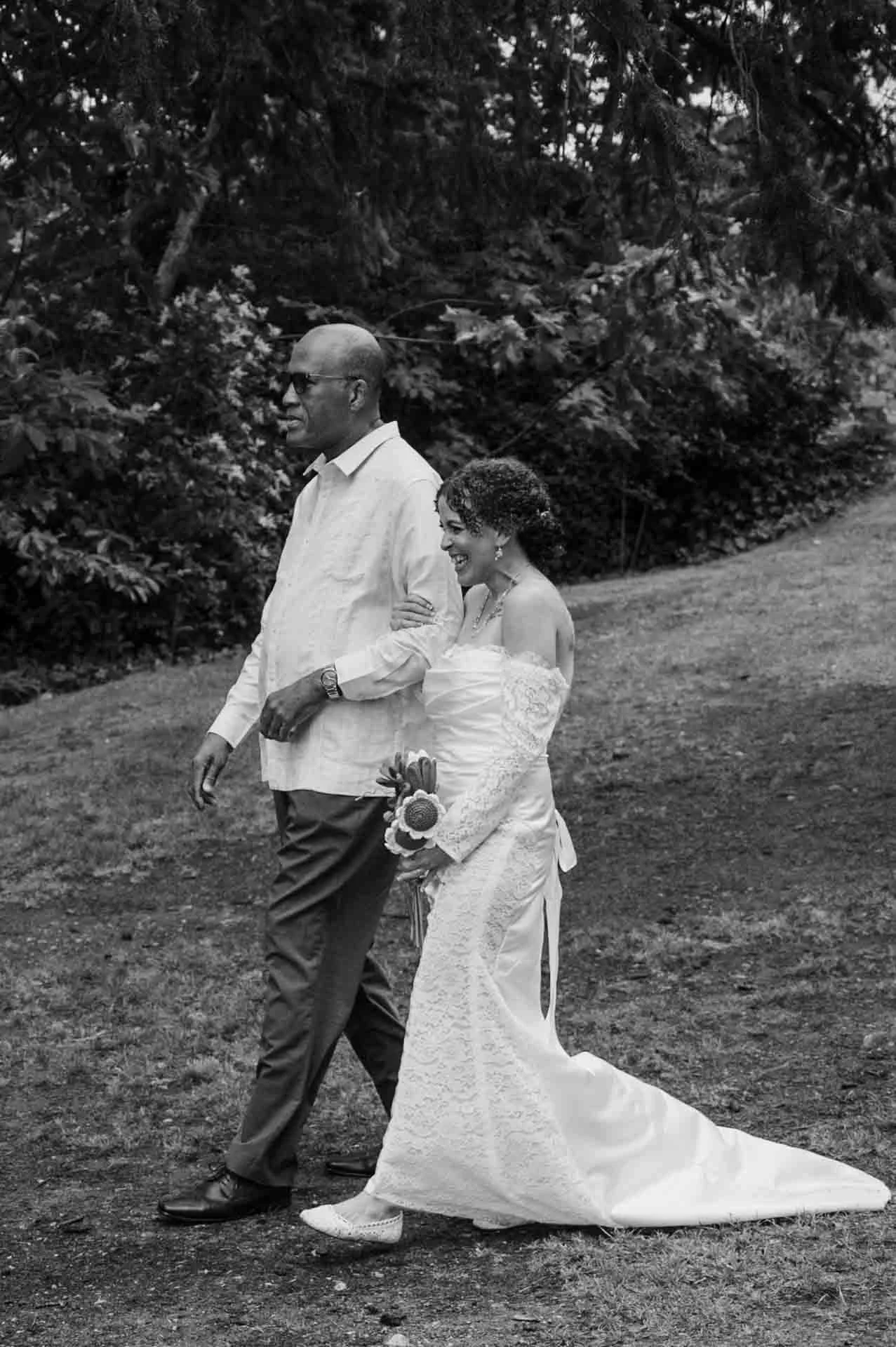 father of bride walking his daughter down a grassy aisle