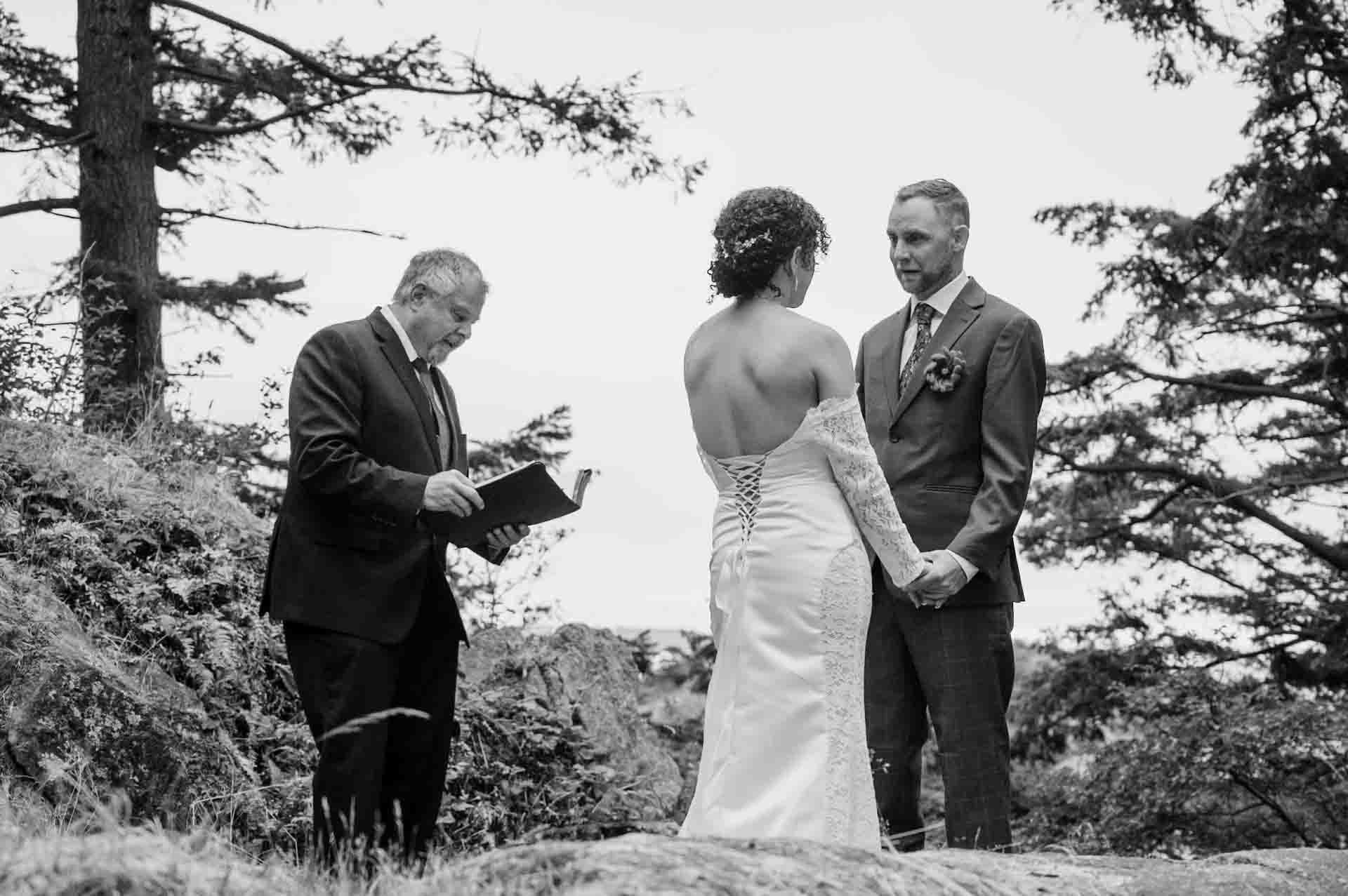 bride and groom holding hands standing infront of officiant at a park