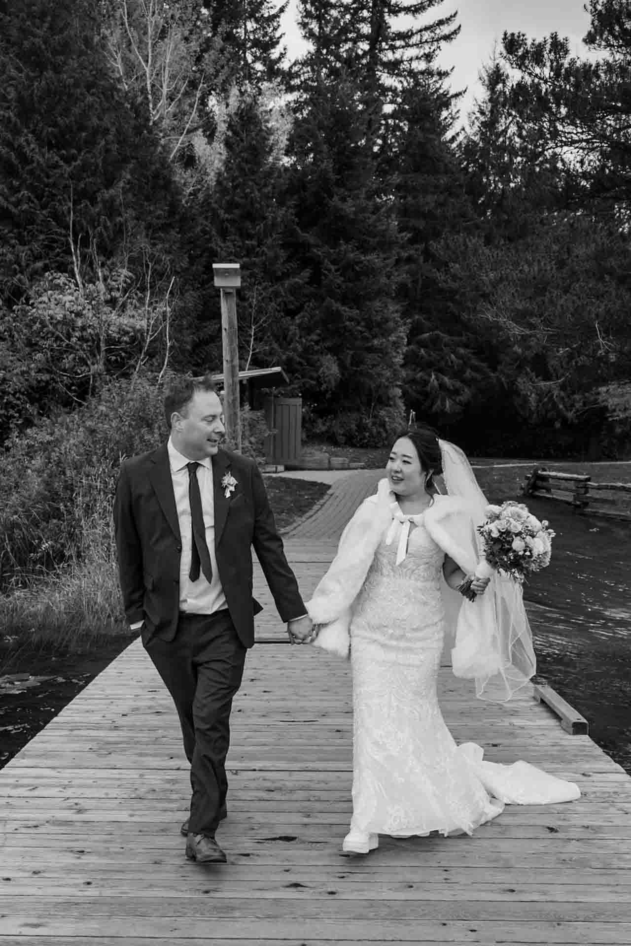 bride + groom walking down a dock holding hands