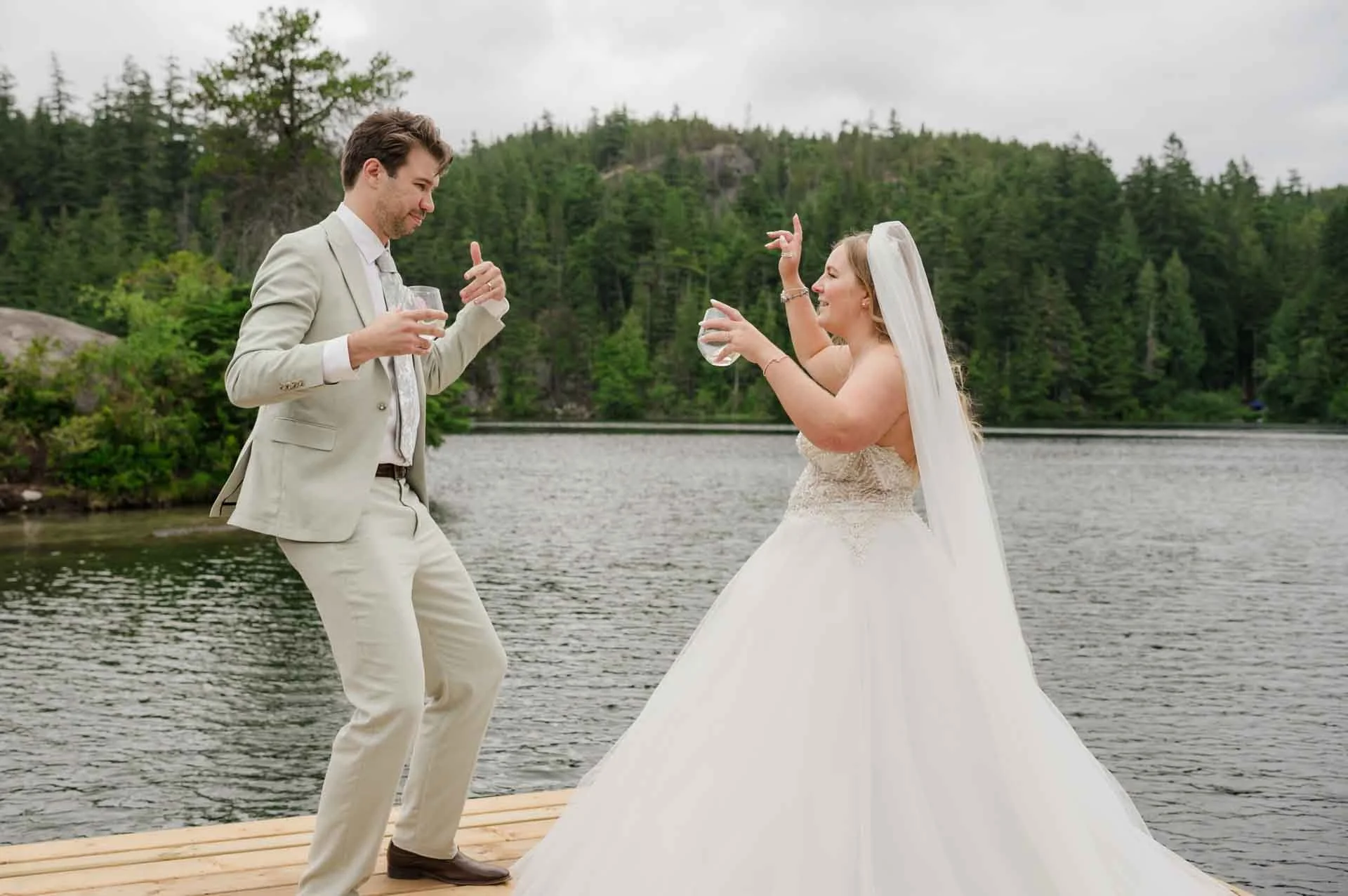 bride and groom dancing on a dock in the middle of a lake