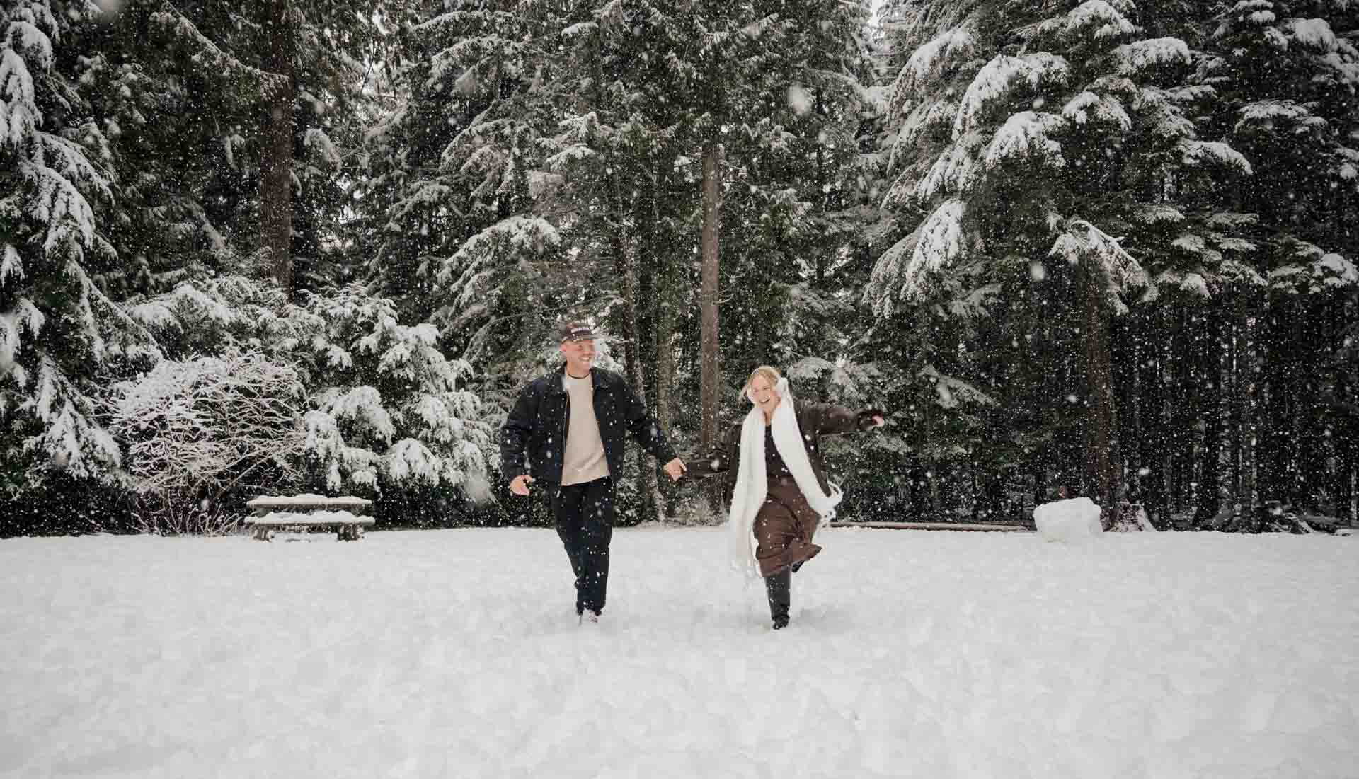 man and woman holding hands running in the snow