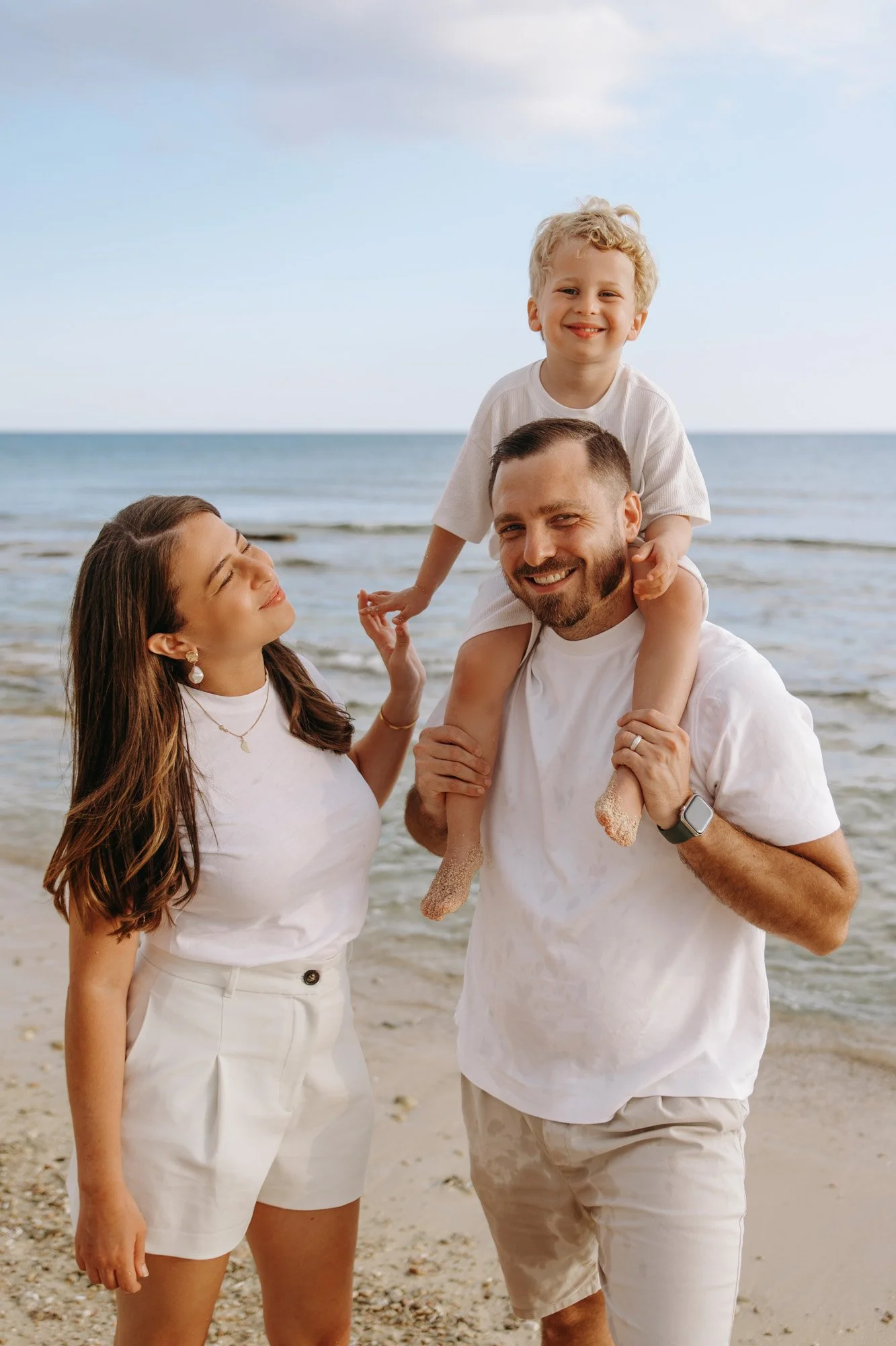 father carrying child on shoulders during family photoshoot Ayia Napa beach