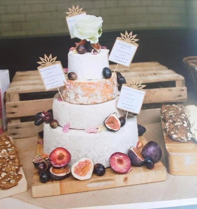 Tre-tiers tårta dekorerad med färska fikon, druvor och små skyltar