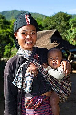 A broad smile stretches across the young mother’s face as she holds her baby close, snug in a plaid cloth slung across her body. The baby peeks out contentedly, one arm tucked beneath the soft folds of the sling, the other resting against the mother’